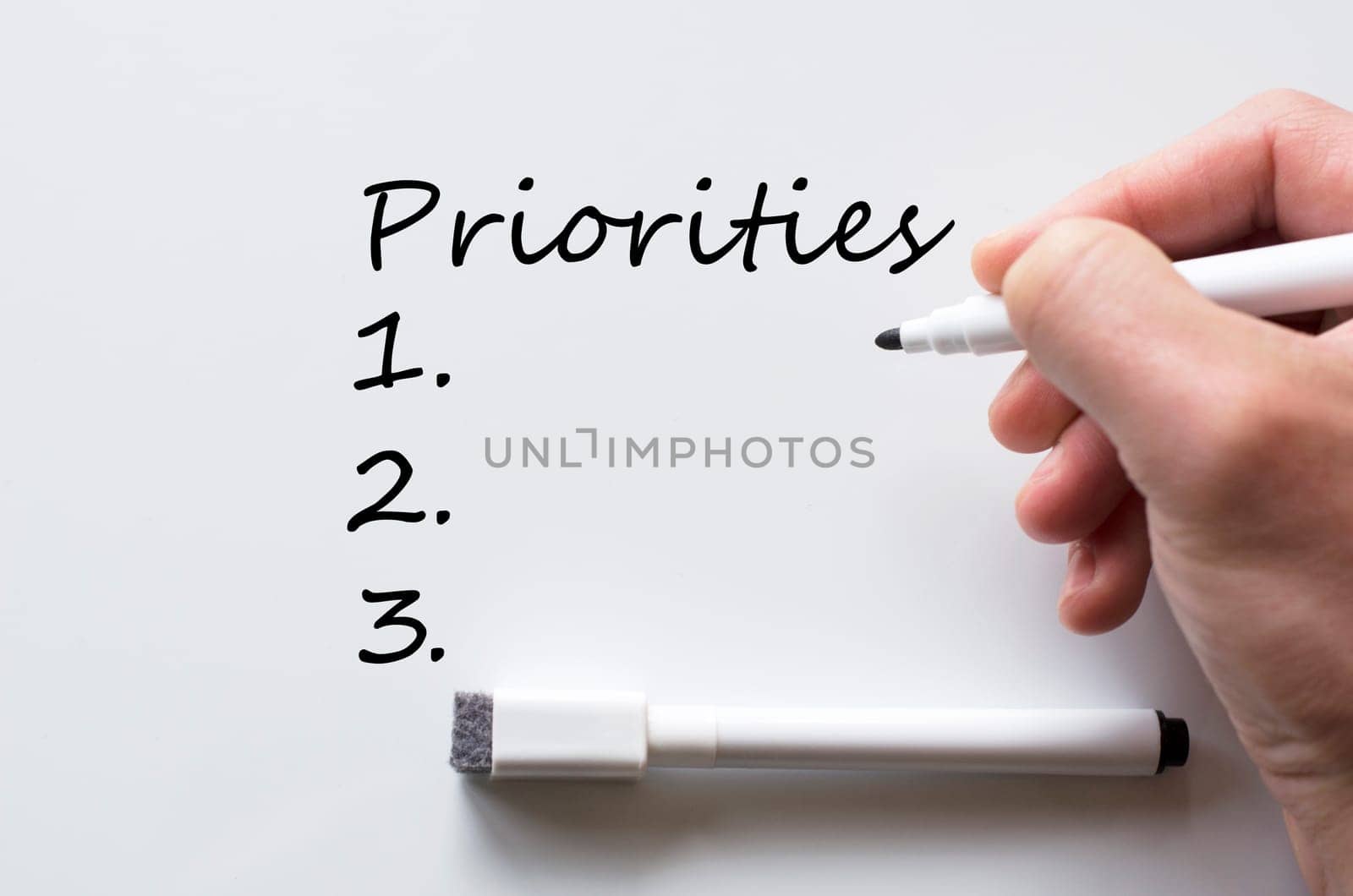 Human hand writing priorities on whiteboard
