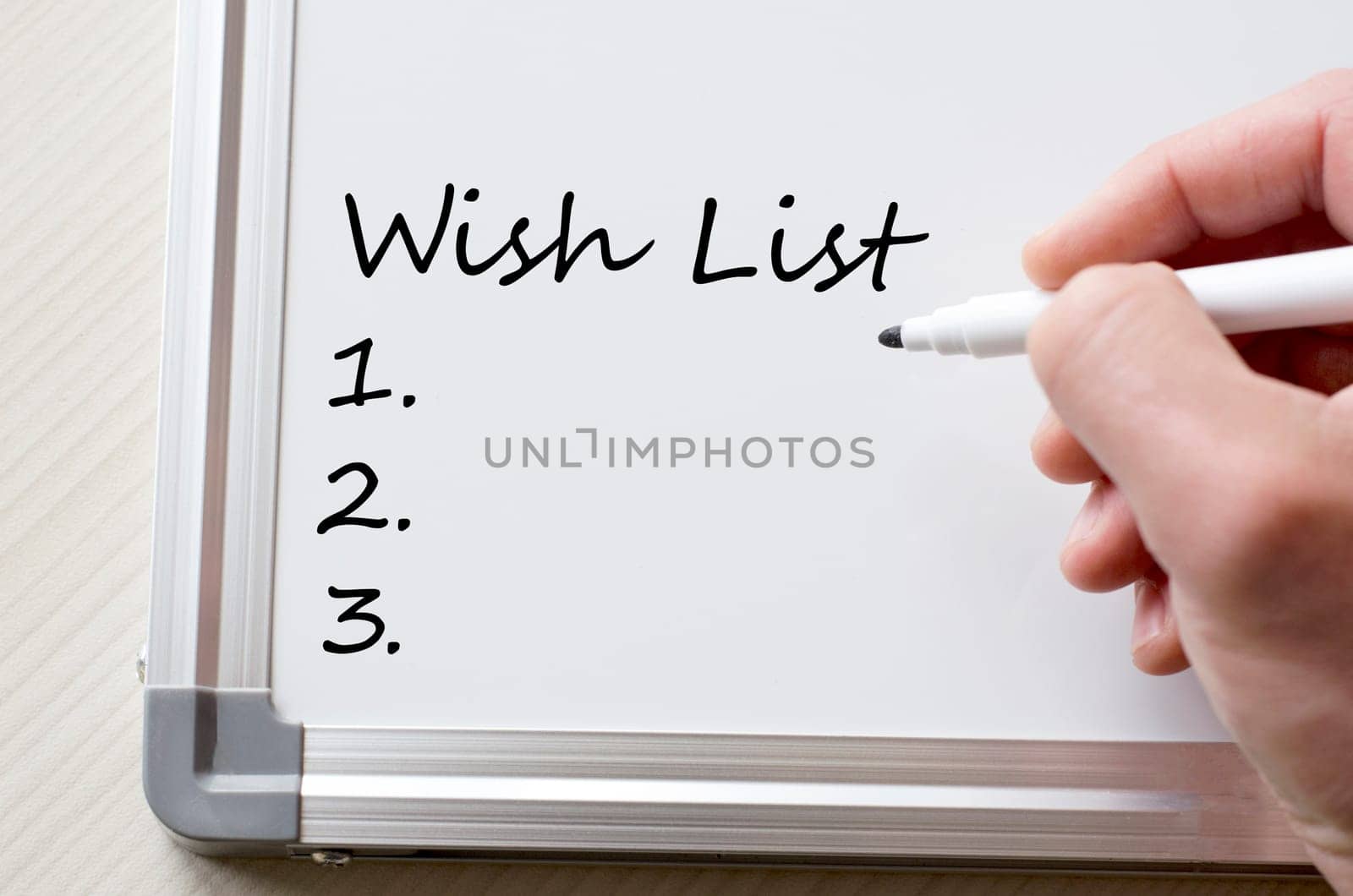 Human hand writing wish list on whiteboard