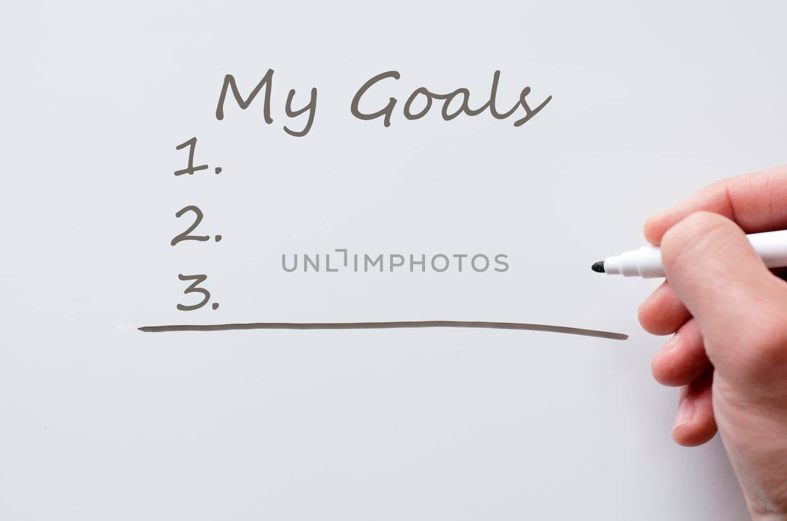 Human hand writing my goals on whiteboard