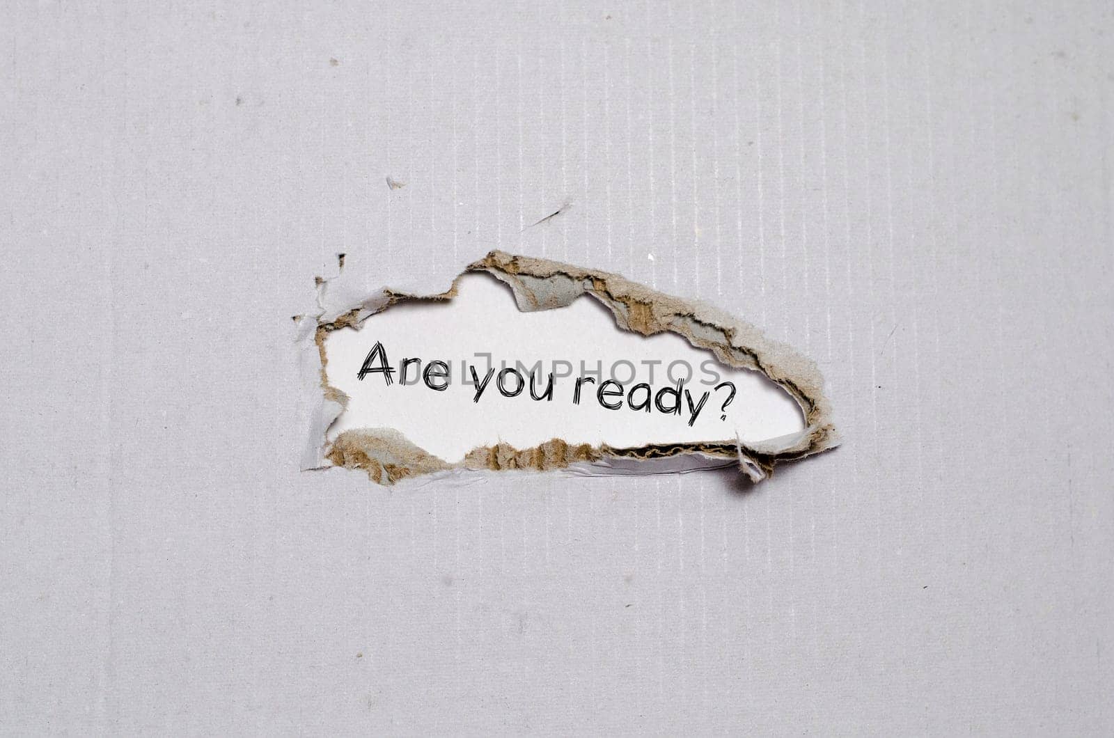 The word are you ready appearing behind torn paper.