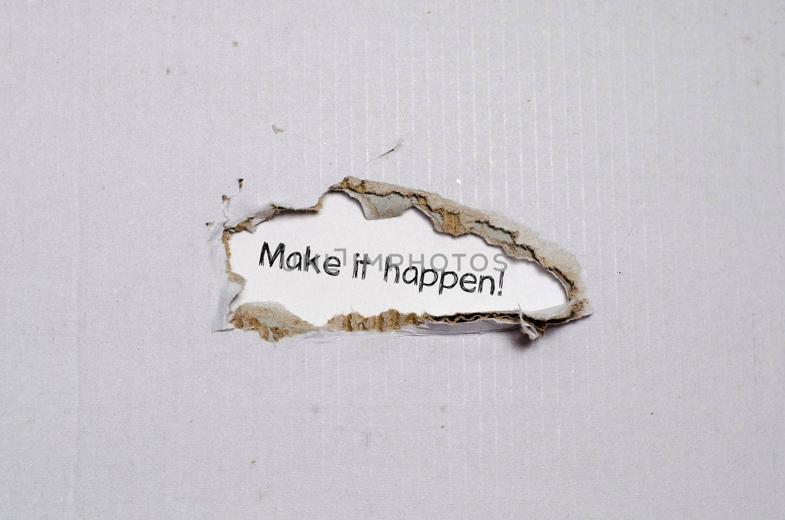 The word make it happen appearing behind torn paper.