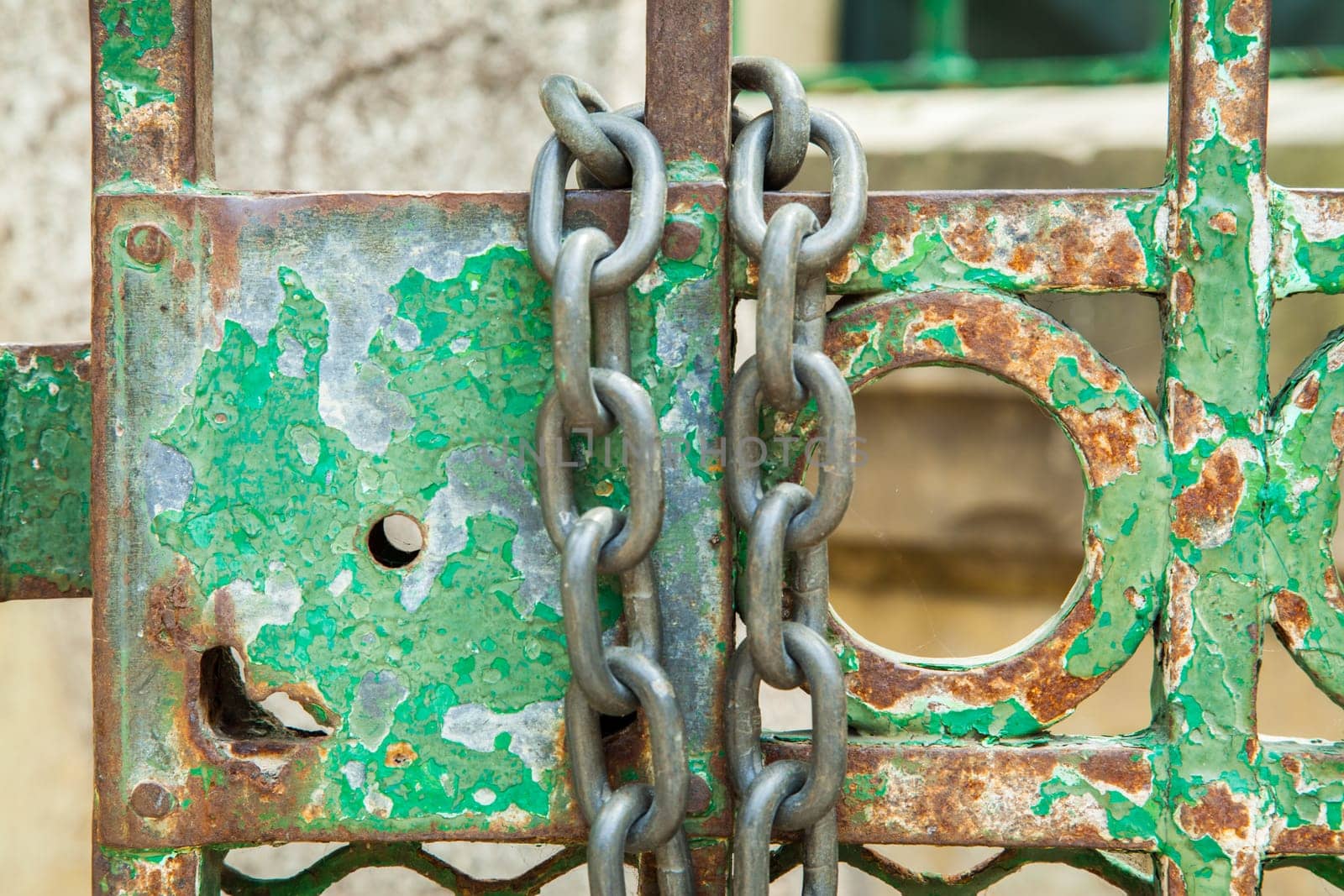 A green rusty lock on an iron door with a chain