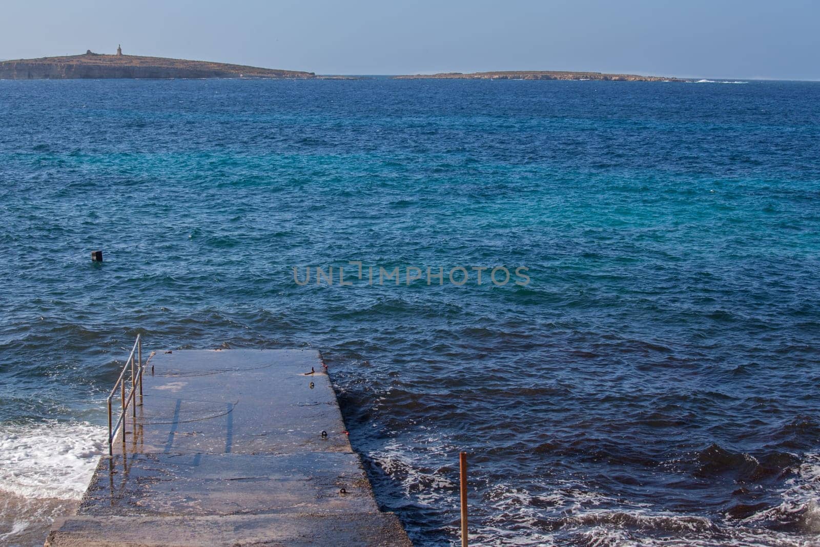 A cemented pier laying over a blue sea