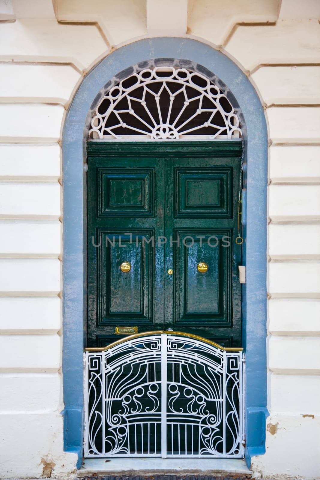 A geen wood door with white small fence and blue frame