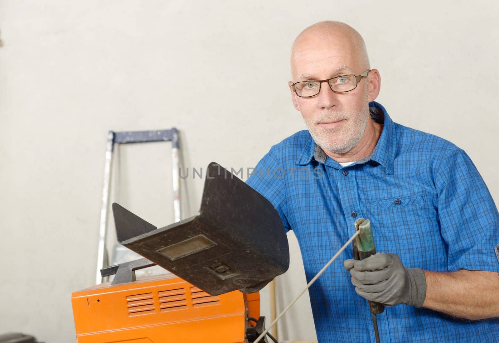 portrait of mature man with a welding station