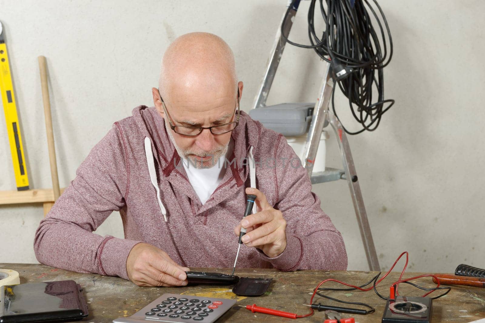 a mature man repairing a smartphone