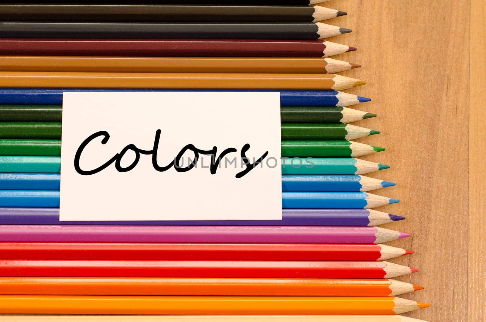 Colors text concept and colored pencil on wooden background