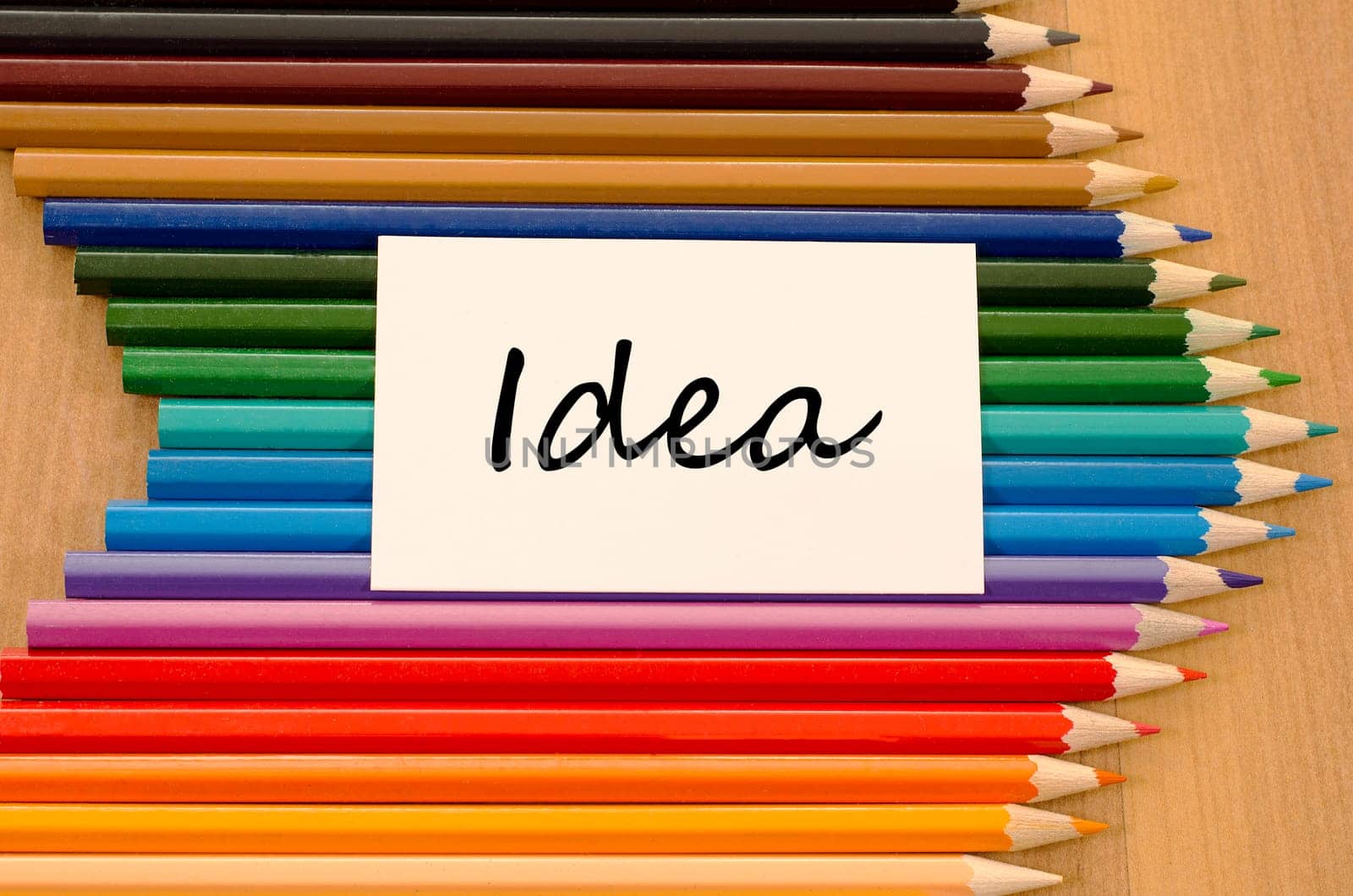 Idea text concept and colored pencil on wooden background