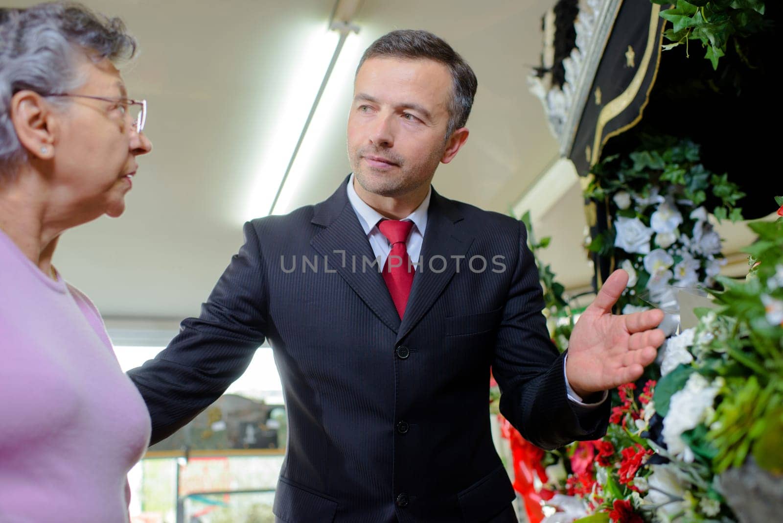 Man advising lady on funeral flowers
