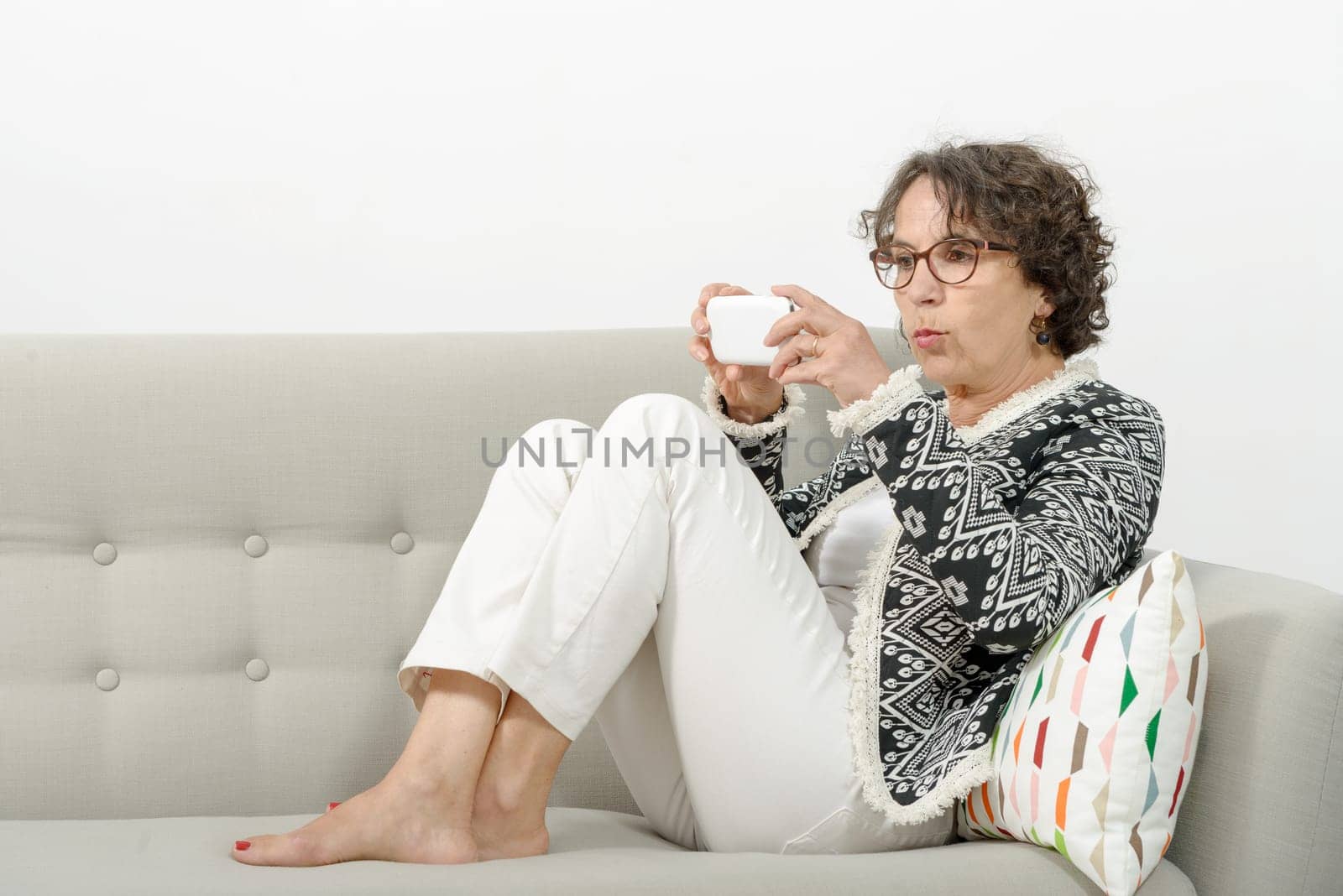 a beautiful mature woman on the sofa with a phone