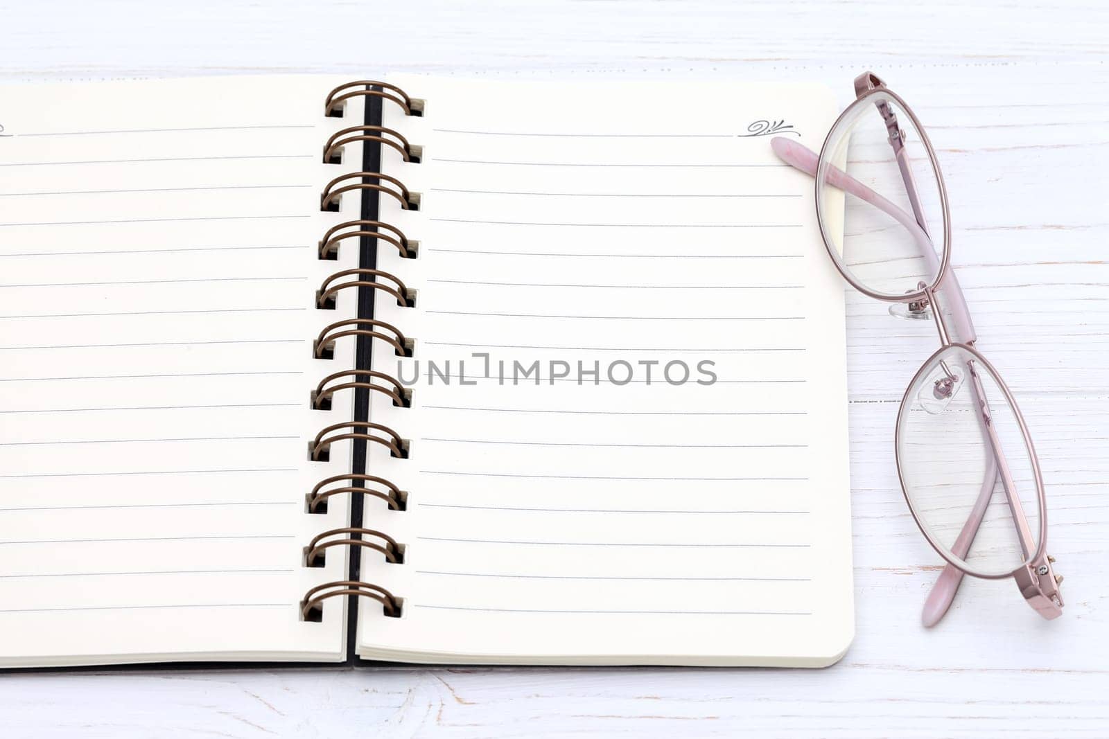 Ladies glasses and notebook on the white wooden table