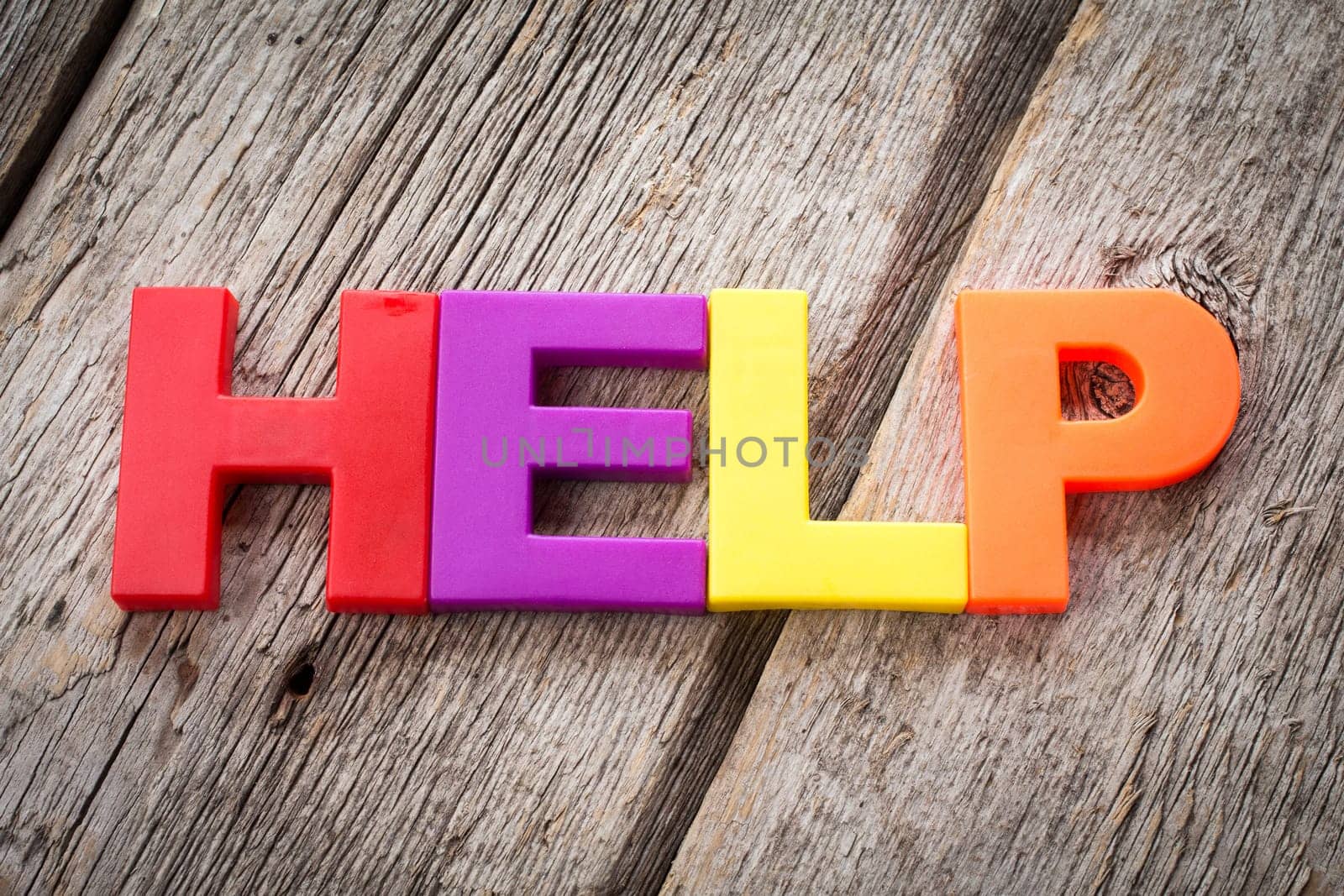 Letter magnets spelling word HELP on wooden background