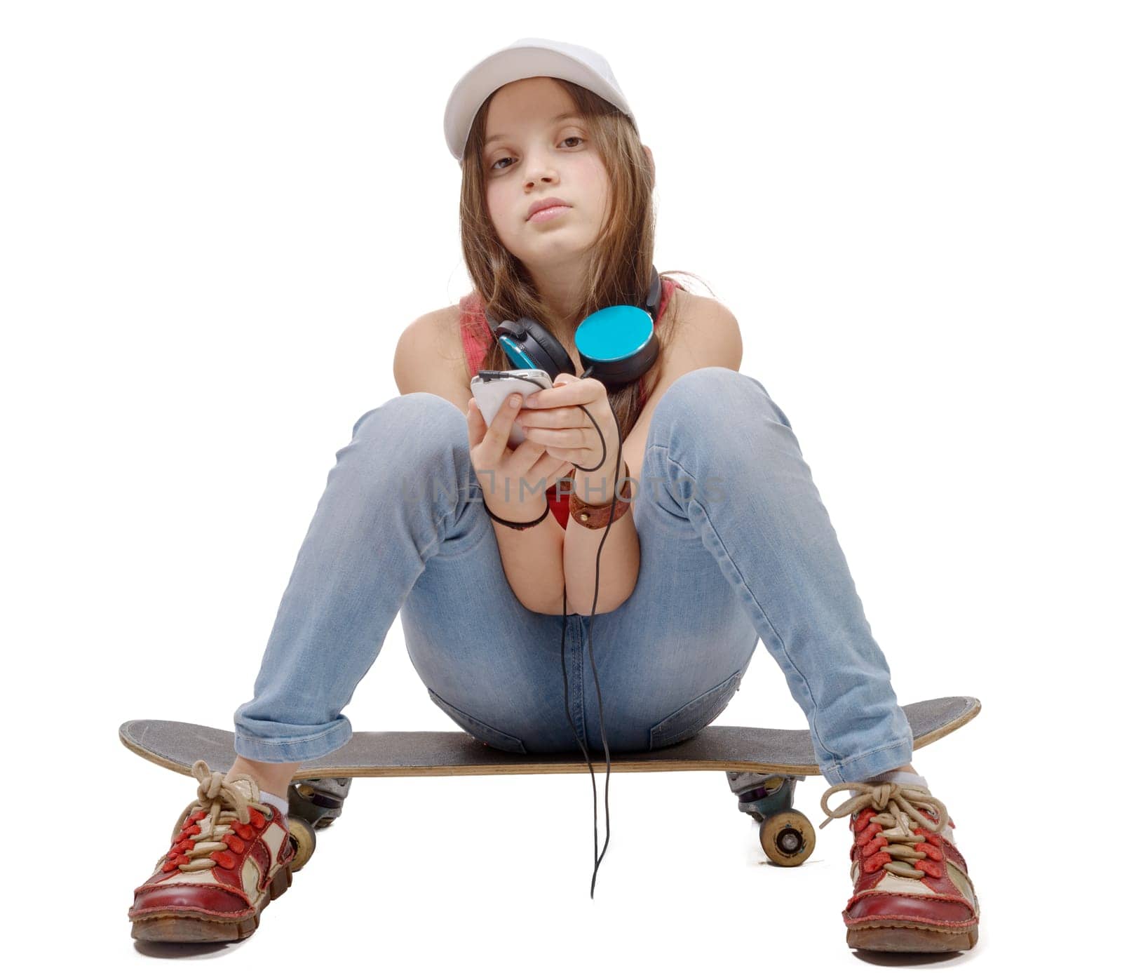 portrait of fashion little girl with blue headphone,sitting on skate, on white