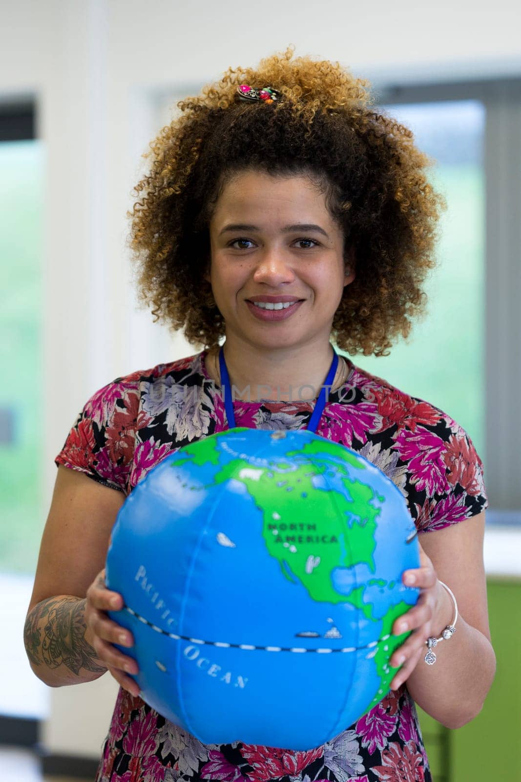 Teacher in a classroom holding a blow up globe to the camera.