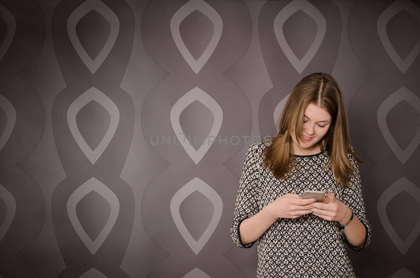 Happy young teenager girl with a mobile phone standing on a wall