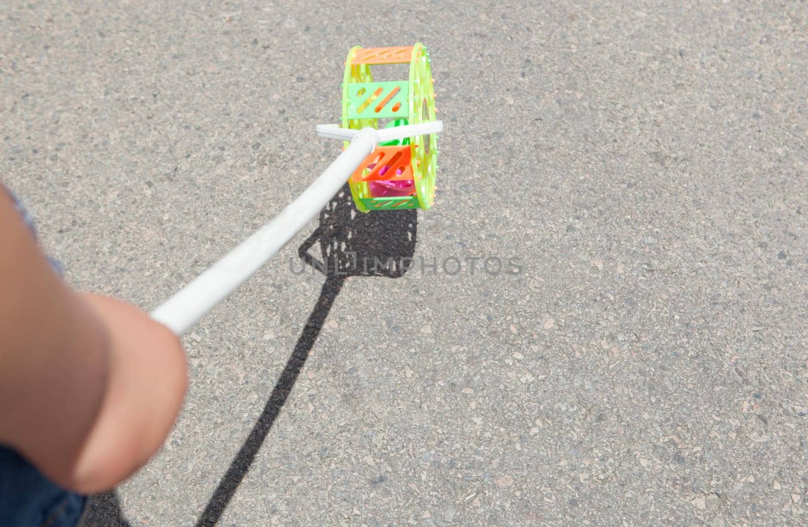 Child with traditional roadrunner wheel toy on street