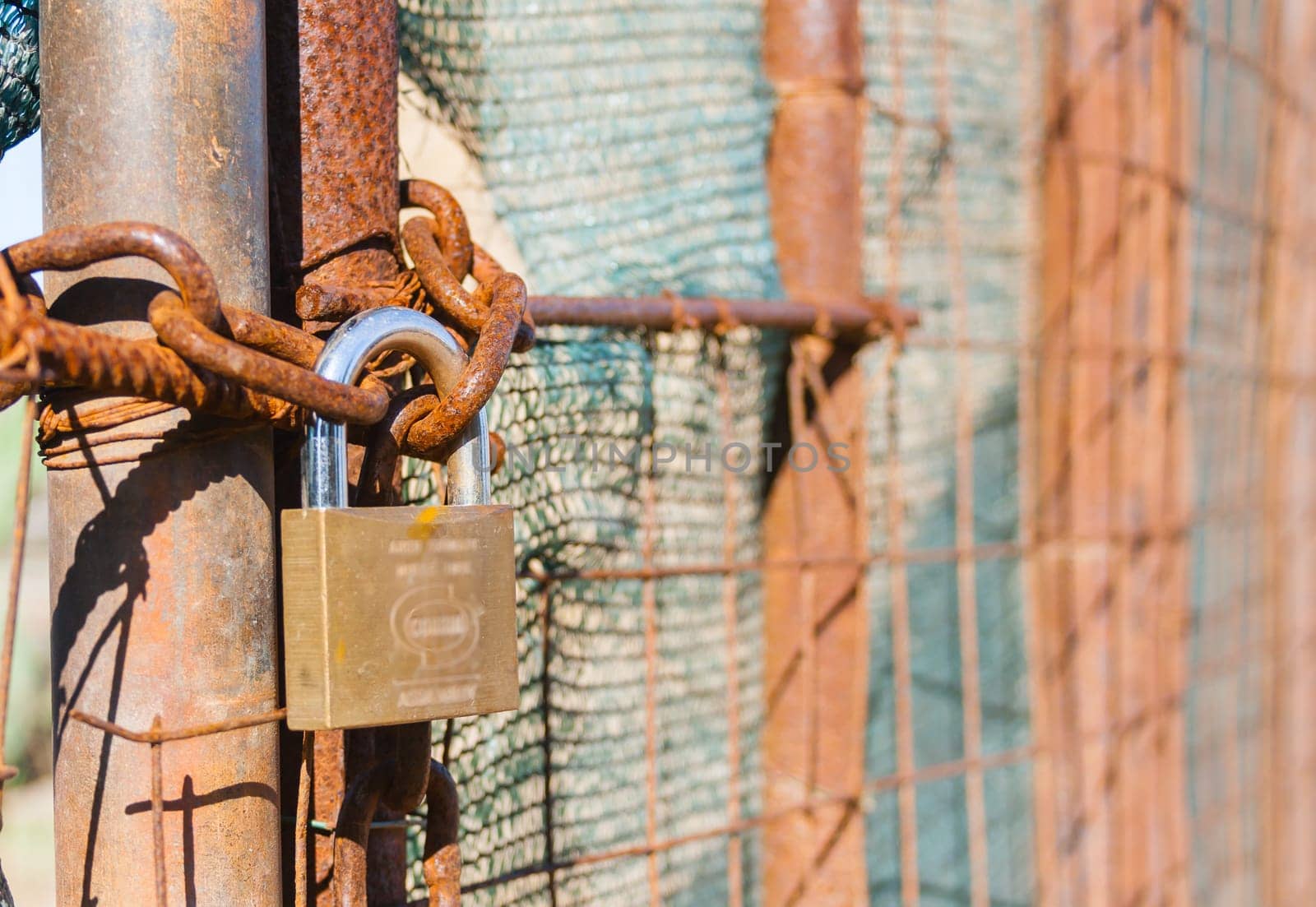 Rusted wire netting in industrial place. Particular of a padlock