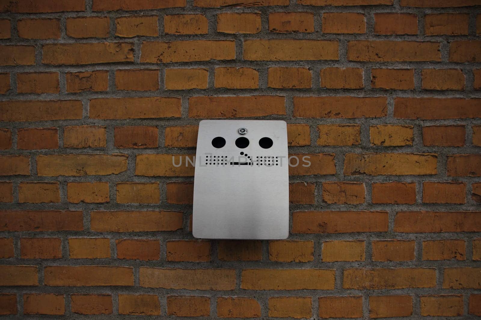Outdoor Grey Steel Ashtray mounted on Yellow Brick Wall