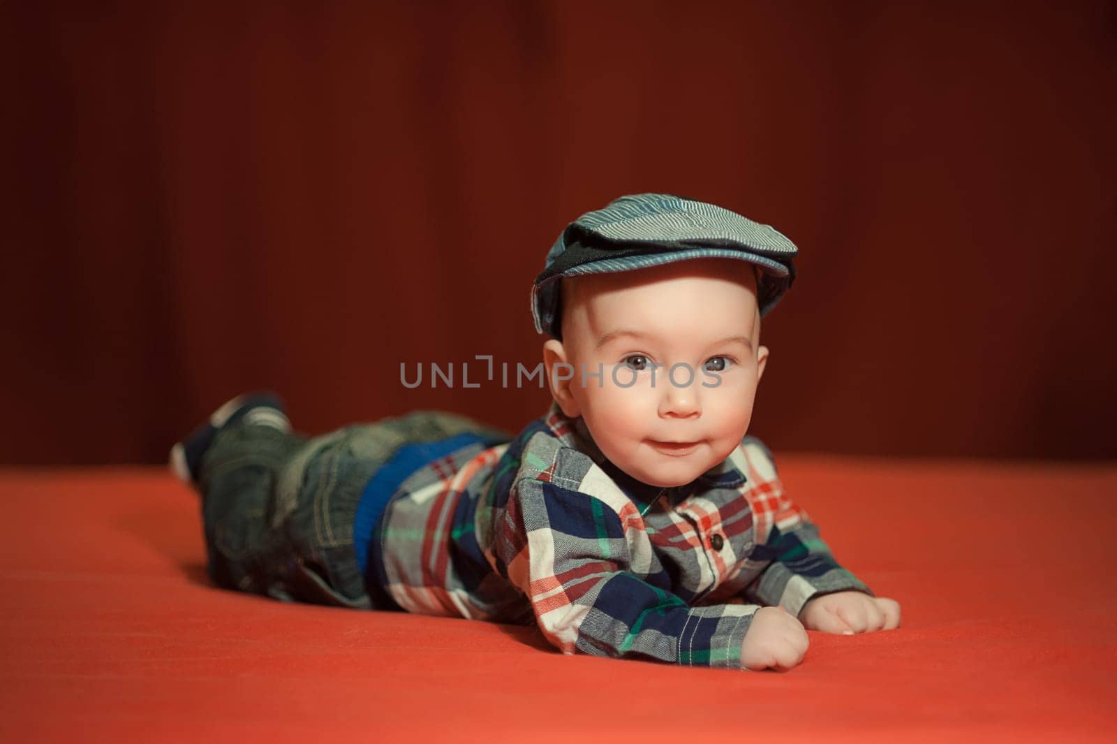 Cute baby in a tweed flat cap with a red background, the child&#39 s emotions
