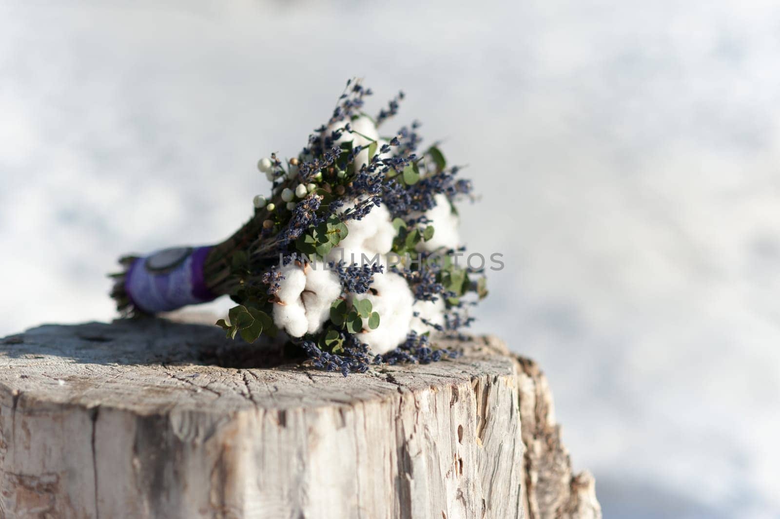 Beautiful wedding bridal bouquet lying on a tree stump made of cotton and blue colors, winter