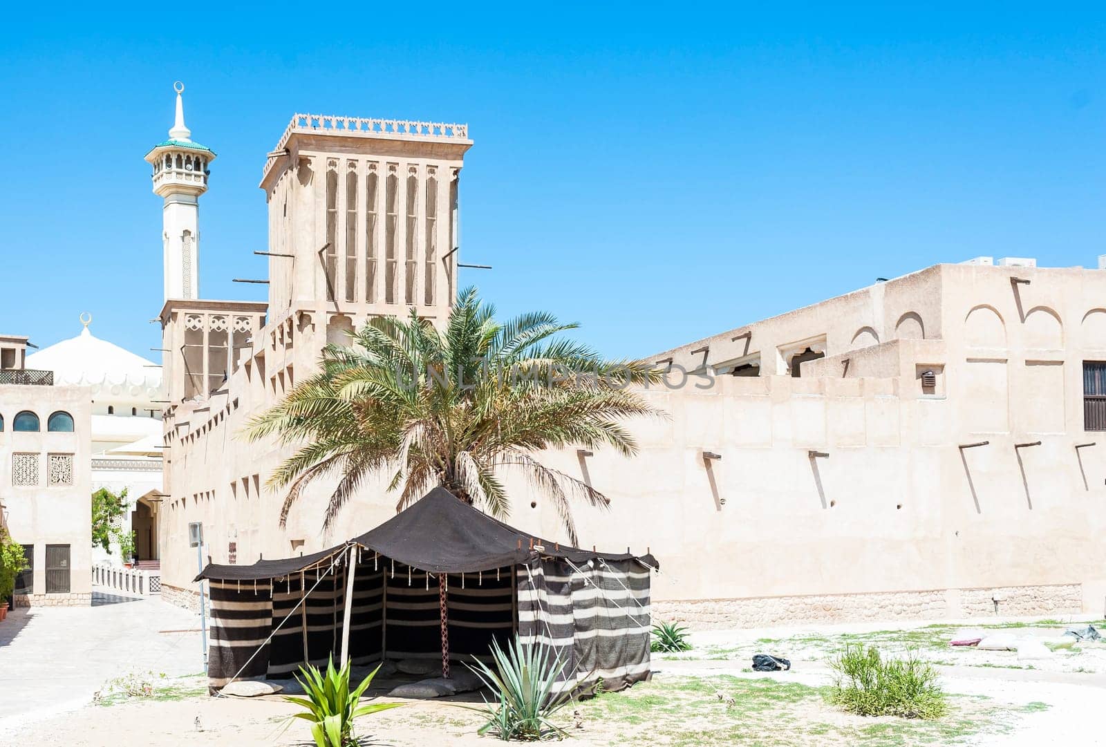 Typical Bedouin tent in front of buildings constructed with typical Arab architecture