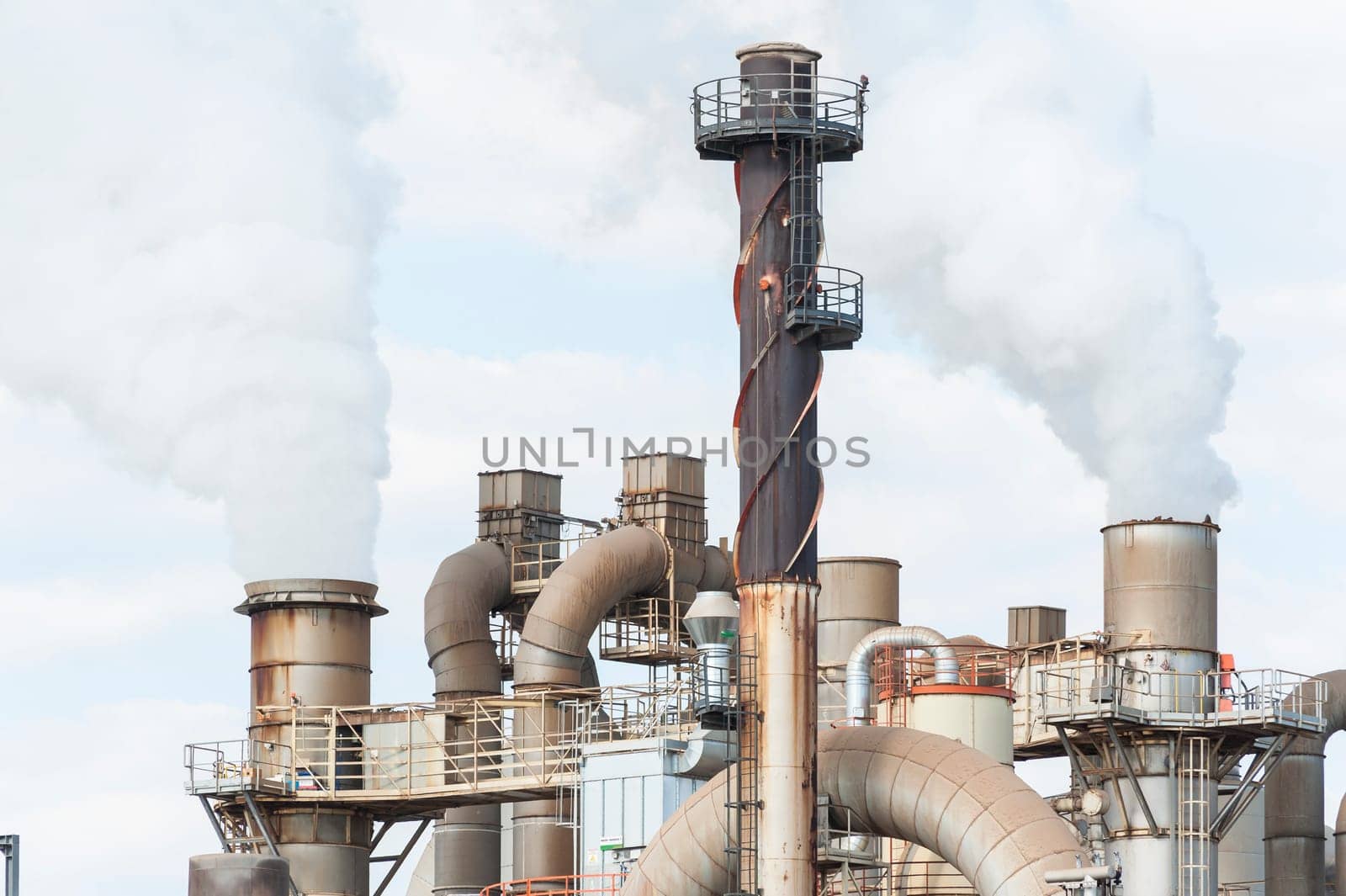 Industrial plant of a furniture factory with smoking smokestack,tube,silos.