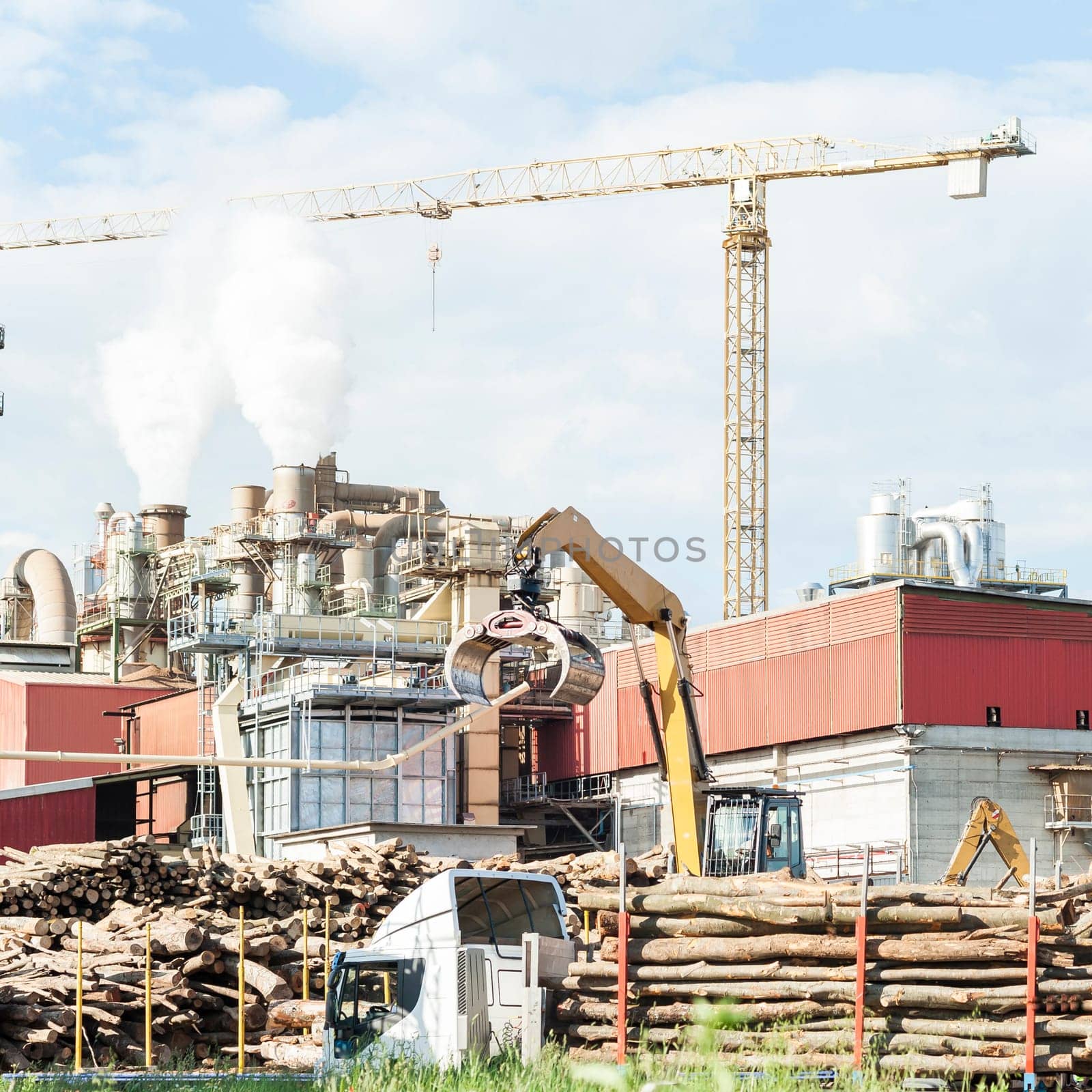 industrial plant of a furniture factory with smoking smokestacks,tubes,silos,crane ,truck and trunks.