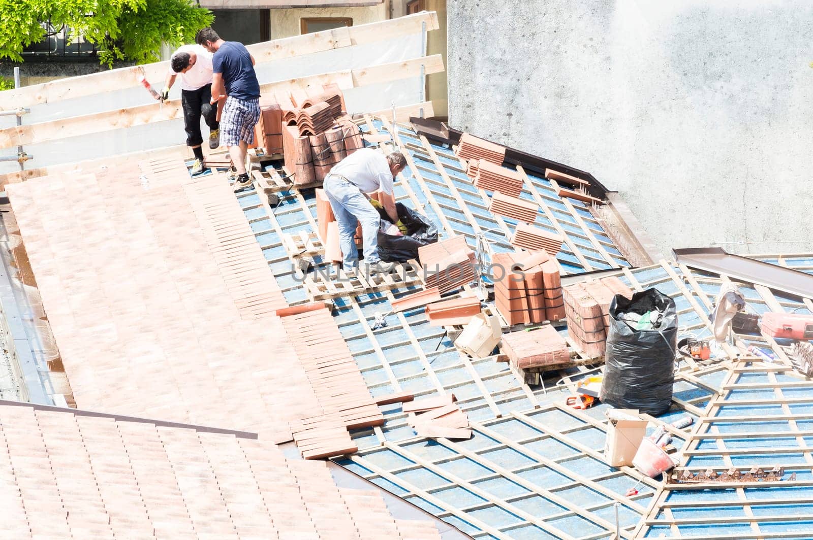 Udine , Italy - May 26 2016 : Construction site. Masons to work on the roof for laying tiles