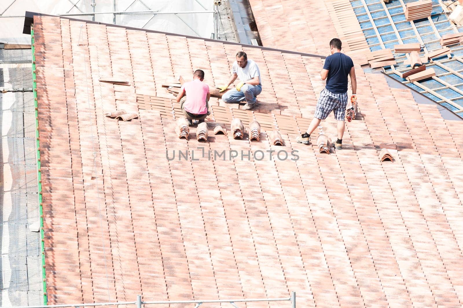Udine , Italy - May 26 2016 : Construction site. Masons to work on the roof for laying tiles