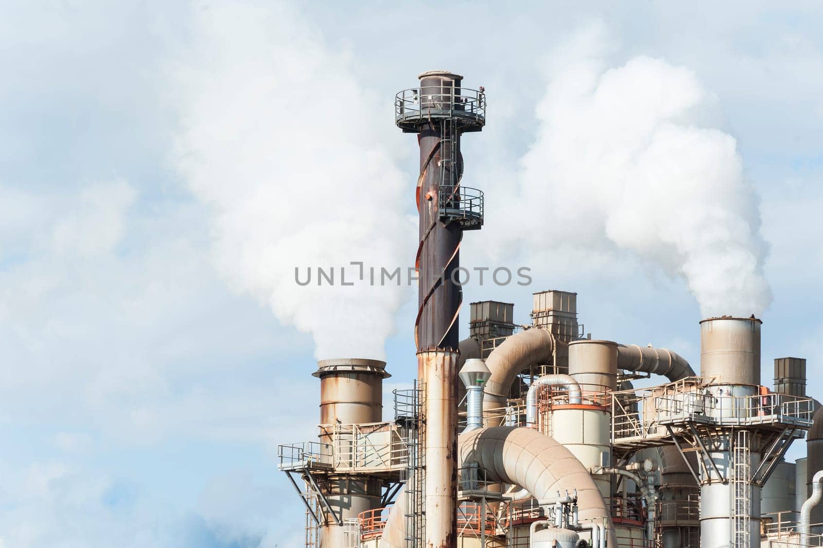 Industrial plant of a furniture factory with smoking smokestack,tube,silos.