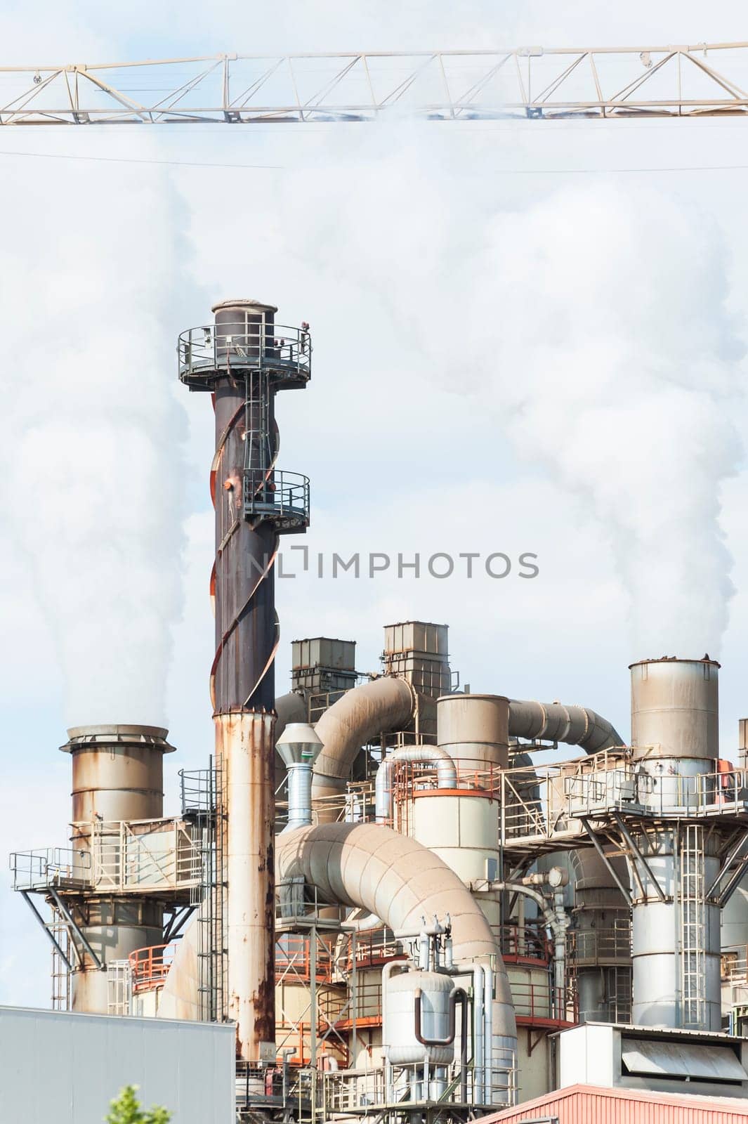 Industrial plant of a furniture factory with smoking smokestack,tube,silos.