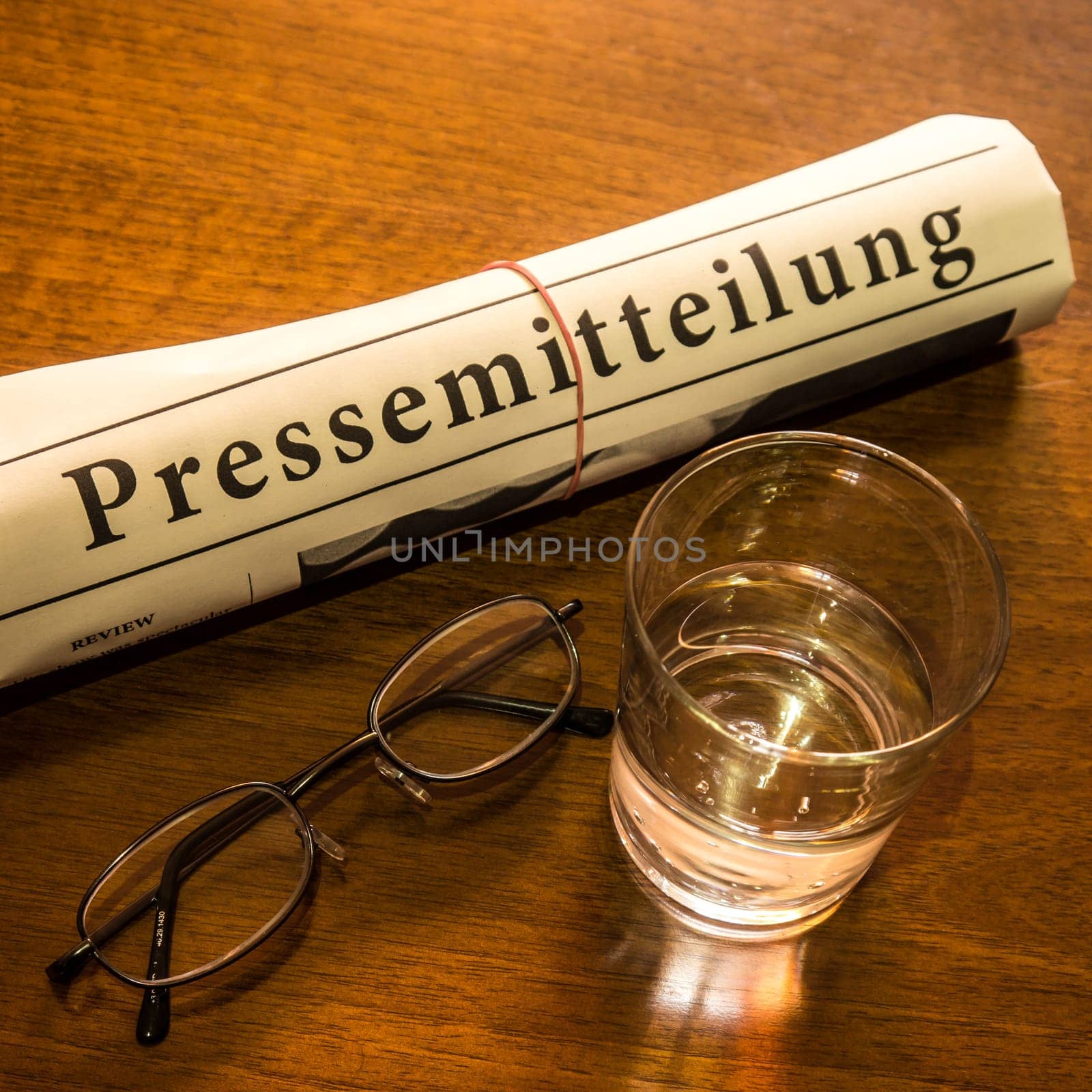 pressemitteilung newspaper, glass of water, glasses on desk