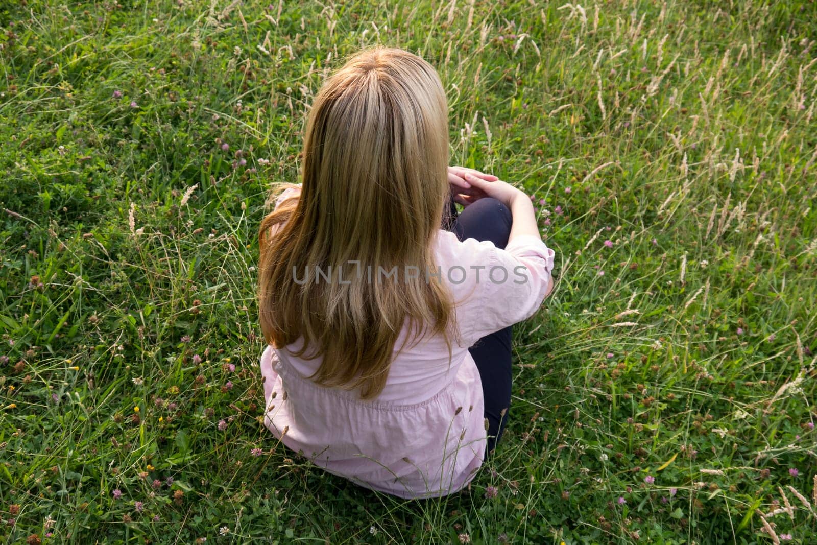 blond long hair woman sitting on meadow