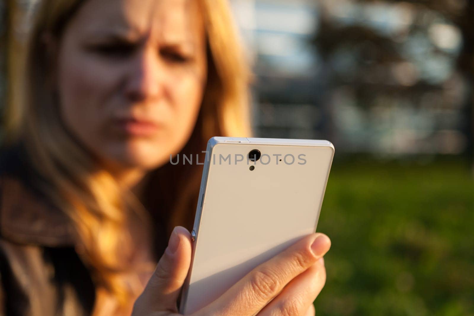 annoyd woman with smartphone in sunlight