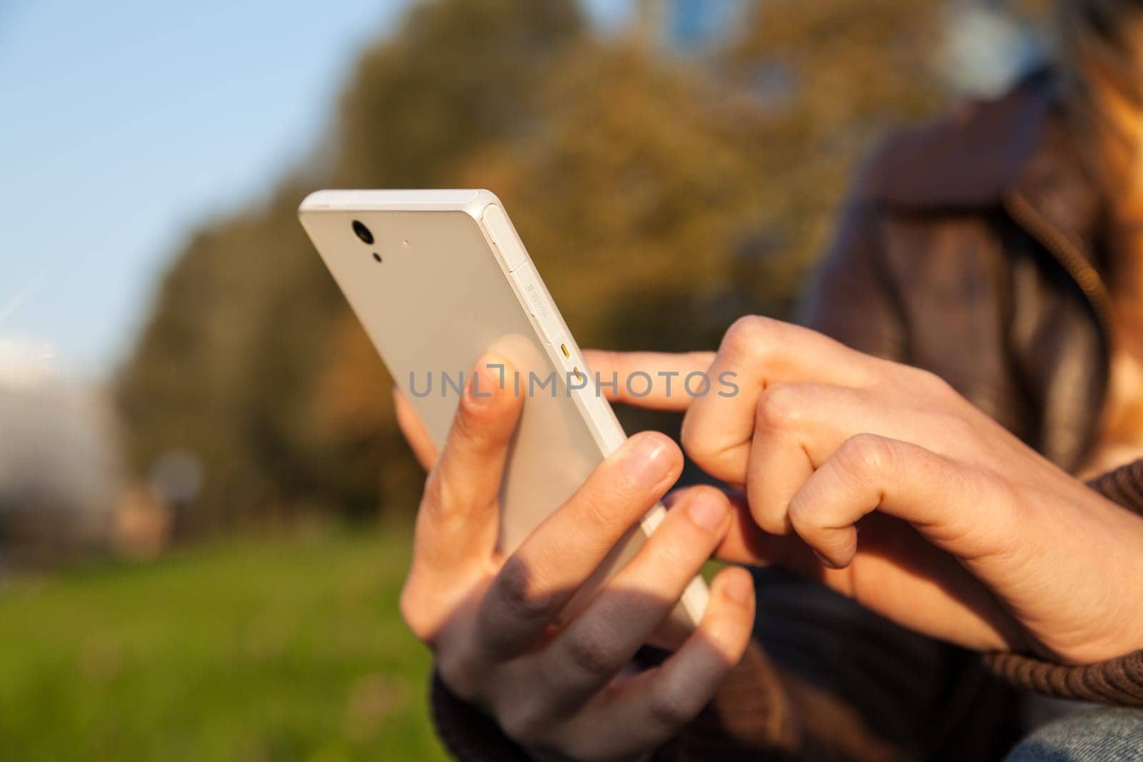 woman's hand holding smartphone in evening time