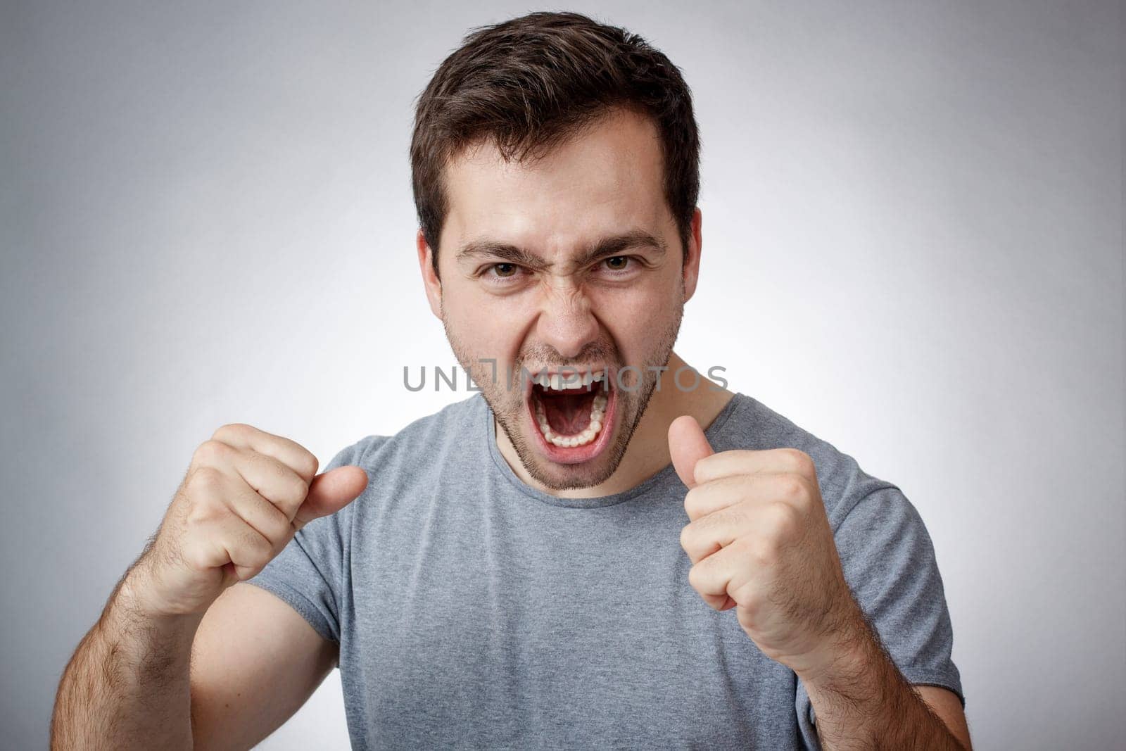 Angry young man clutching fists and shouting