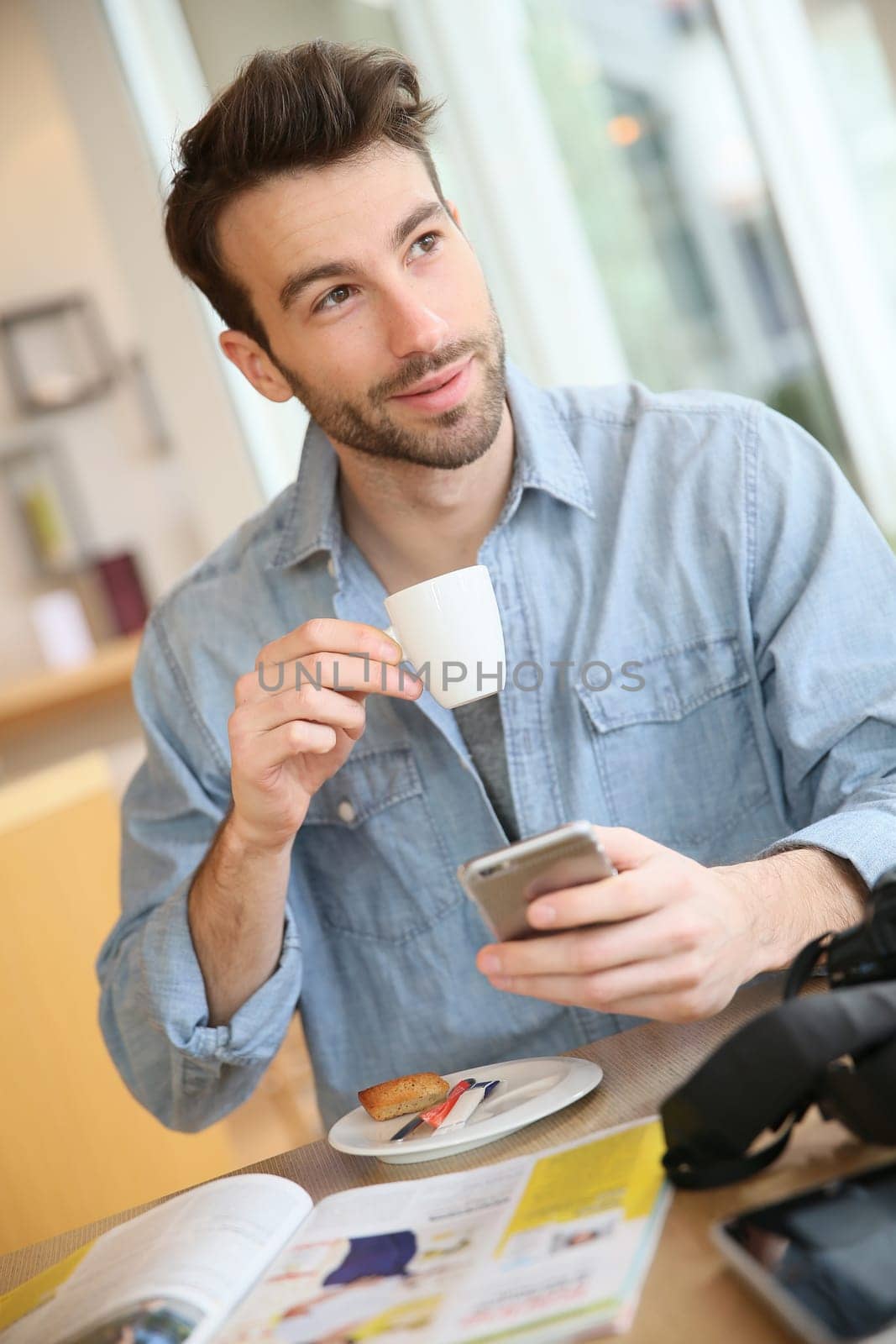 Man in coffee shop sending message with smartphone
