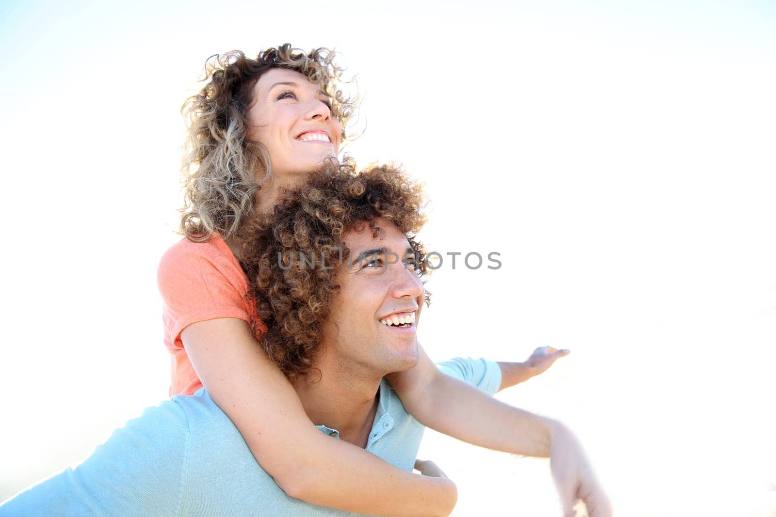 Man giving piggyback ride to girlfriend on the beach
