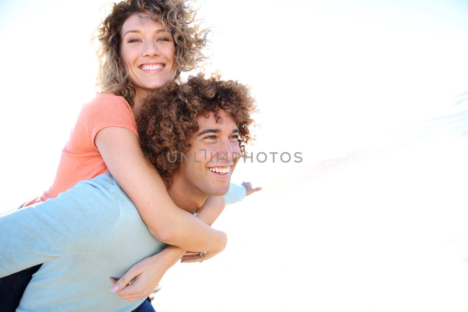 Man giving piggyback ride to girlfriend on the beach