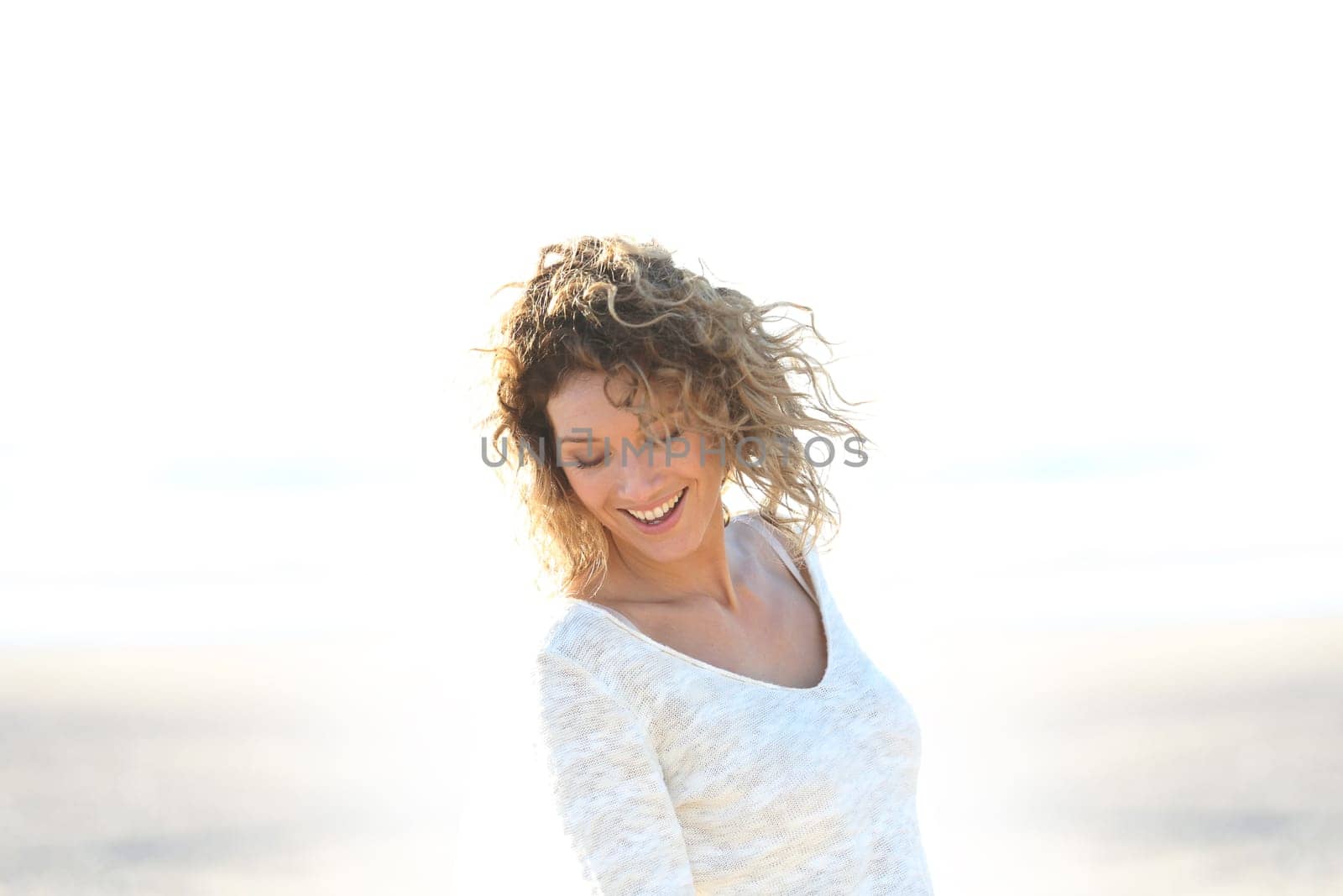 Beautiful smiling blond woman standing on a beach