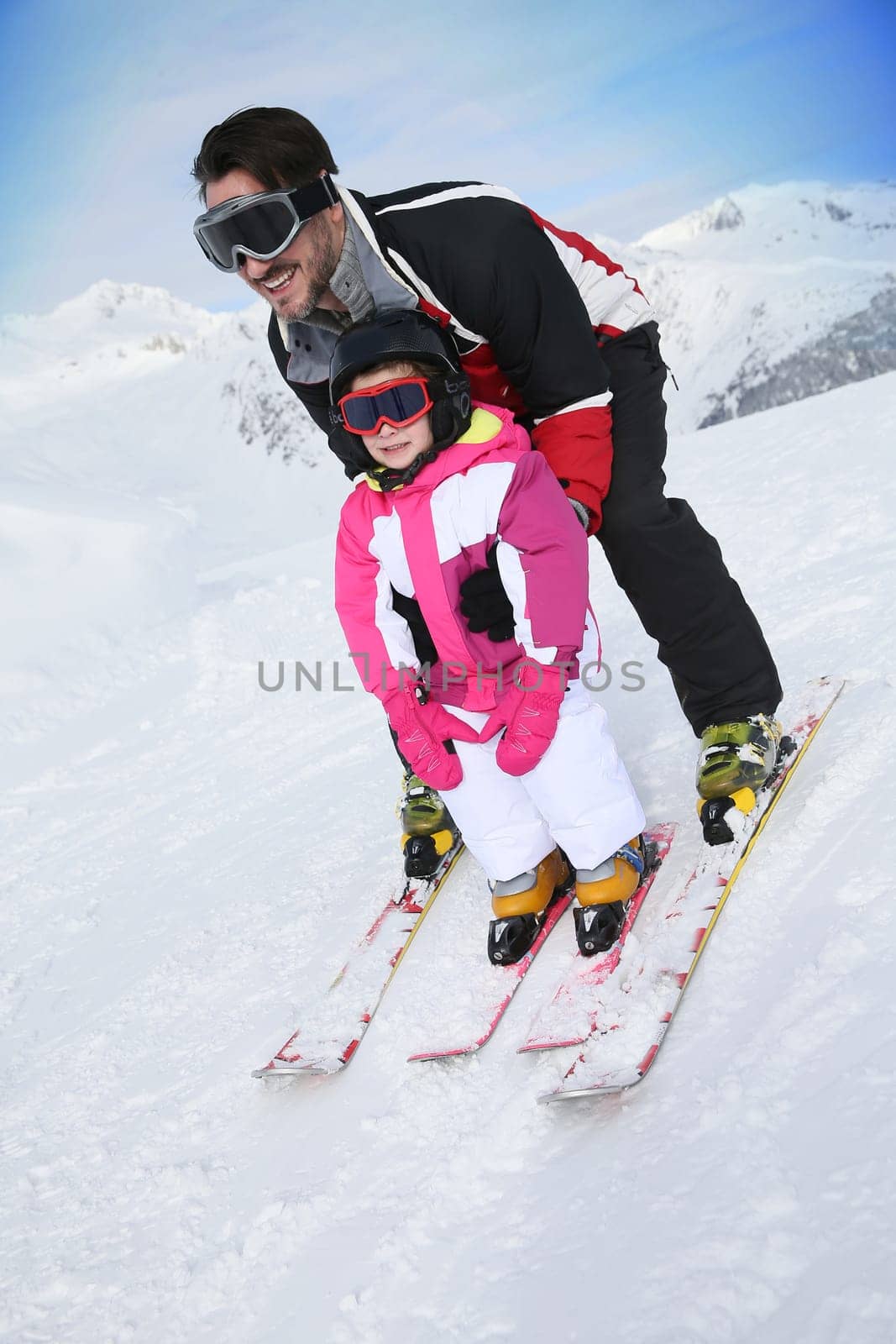 Daddy with little girl skiing down slope