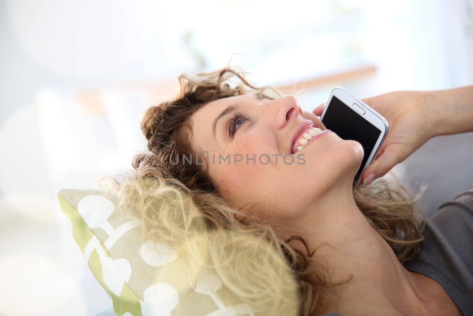 Woman talking on smartphone laid in sofa