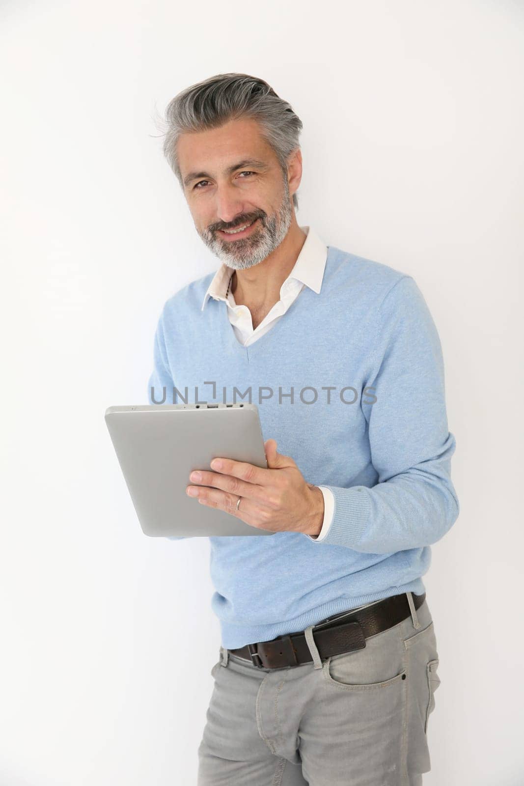 Handsome mature man websurfing with tablet, isolated