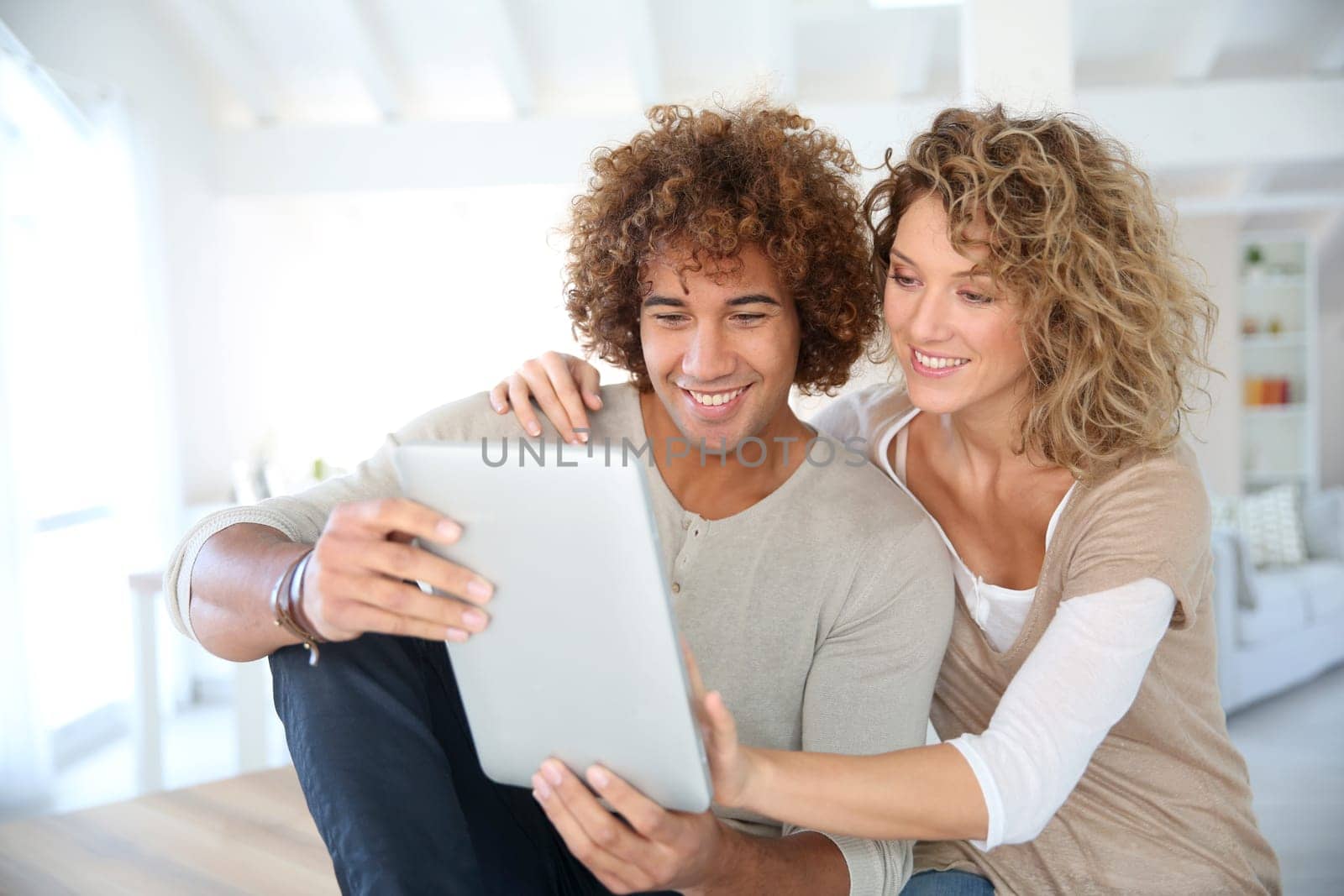 Happy couple at home websurfing on digital tablet