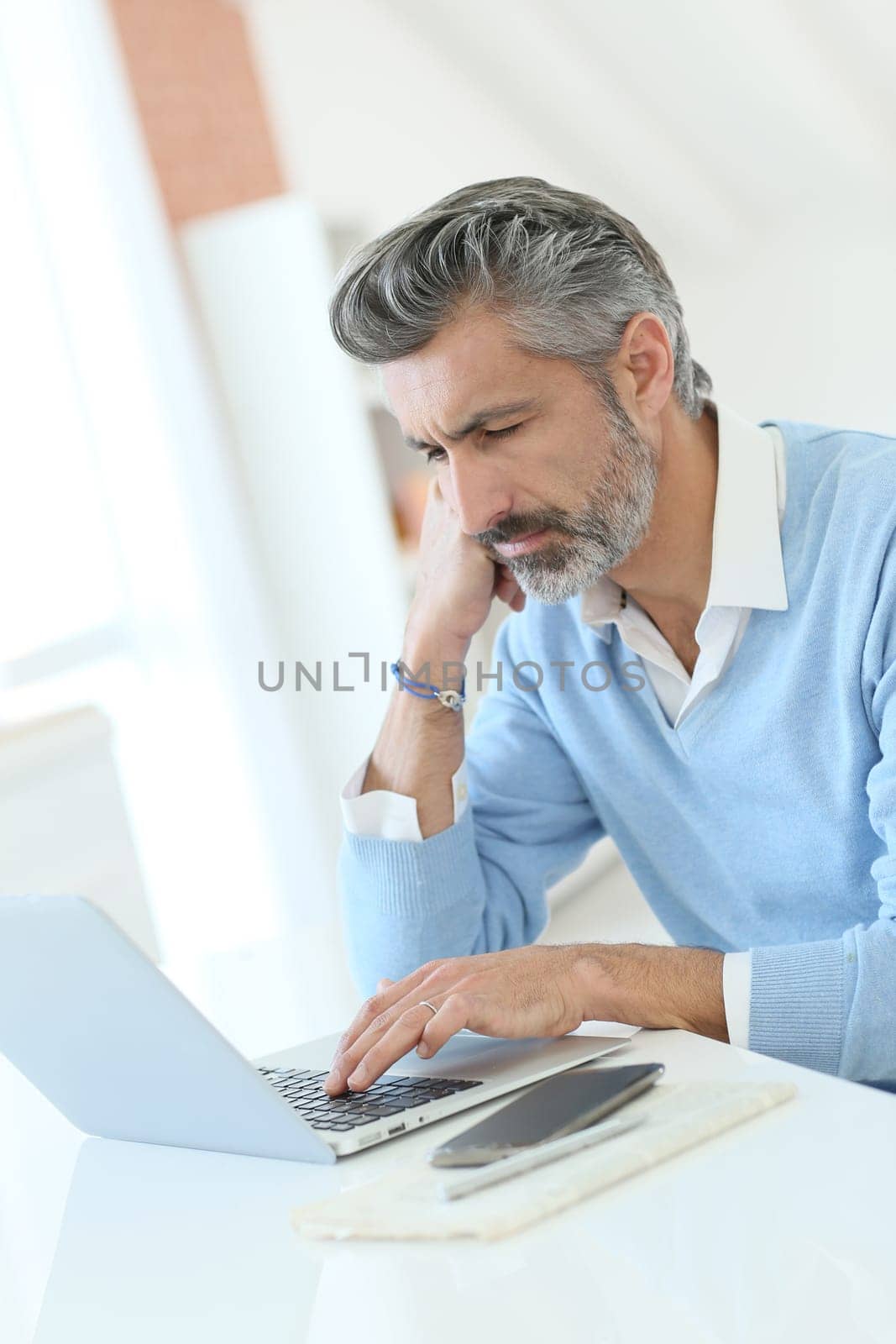 Trendy mature man working from home with laptop