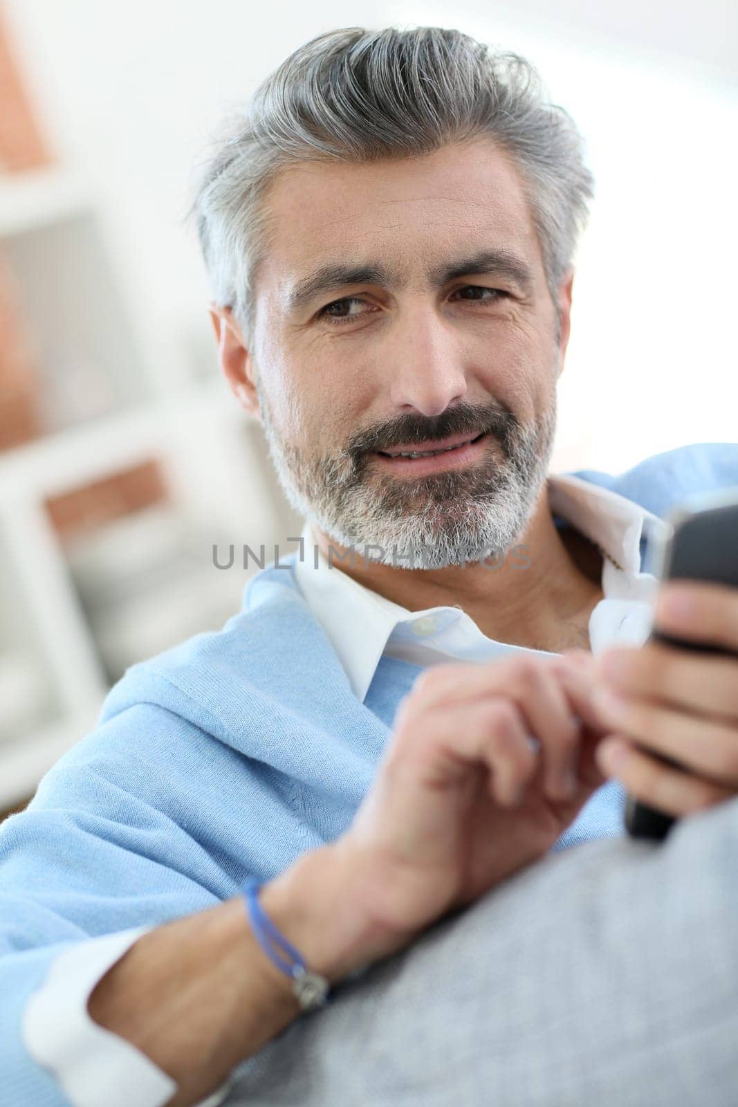 Mature man sending message with smartphone