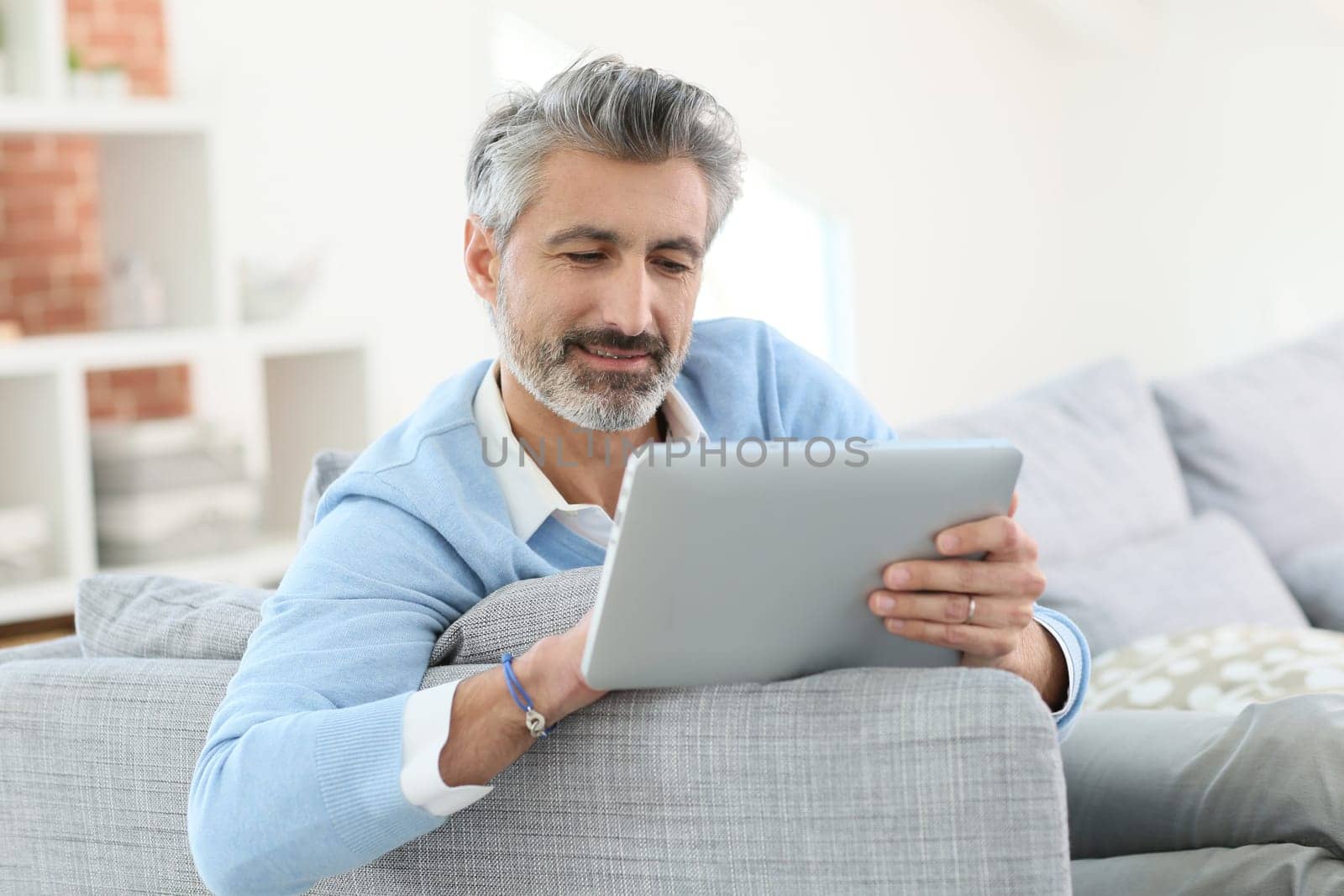 Mature man sending email with digital tablet