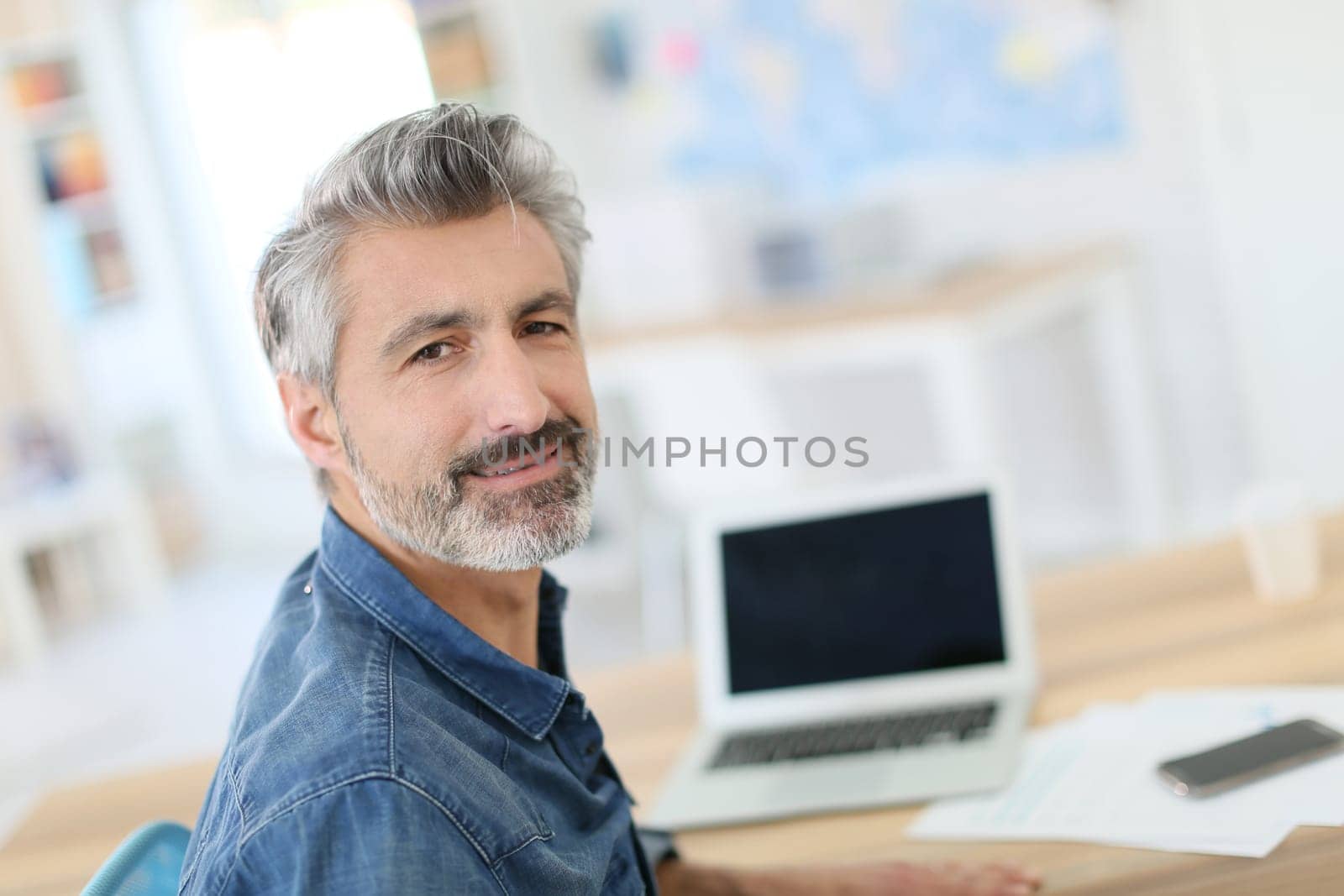Mature man working on laptop in school office