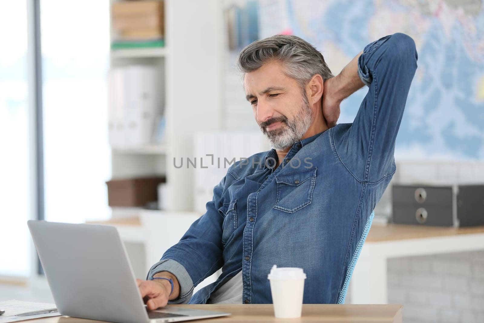Mature man relaxing in front of laptop in class