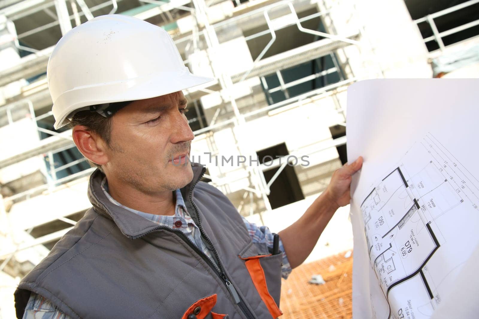 Construction manager on building site holding blueprint